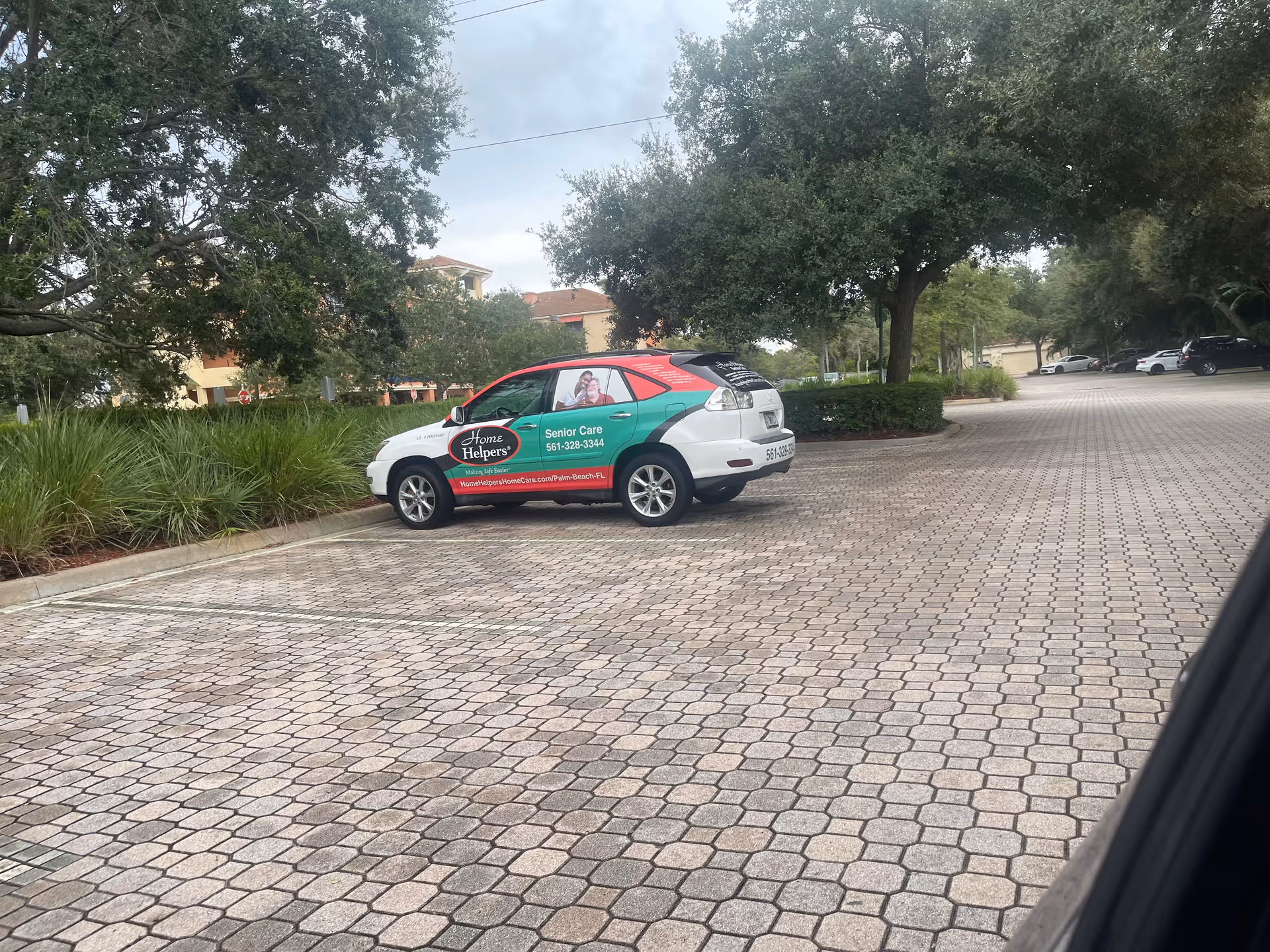 A branded Home Helpers Senior Care vehicle parked in a curved brick parking lot.