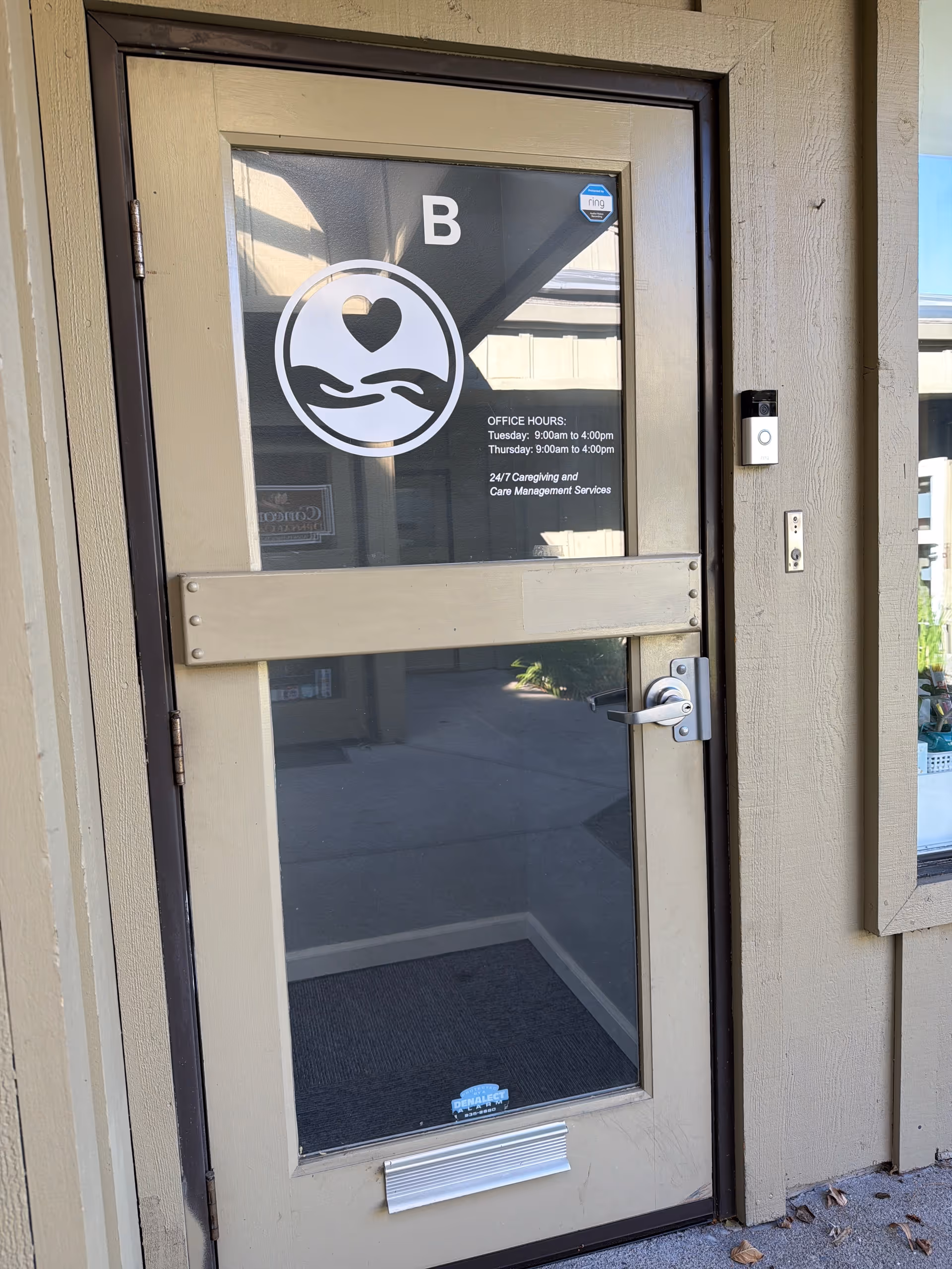Glass door entrance with a heart logo, metal bar, and exterior wall on a building front.