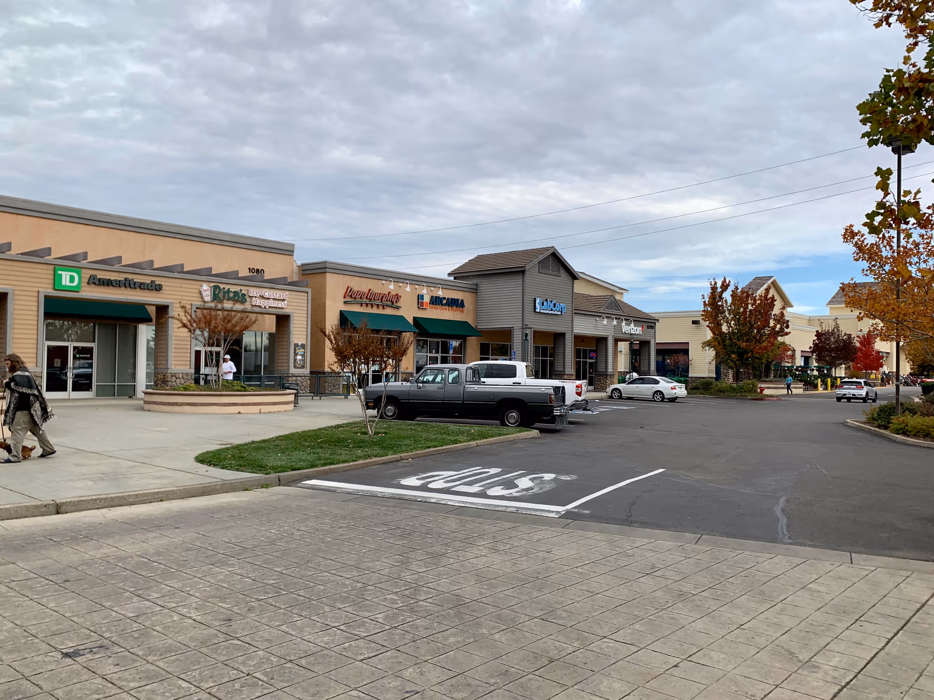 Arcadia Home Care & Staffing storefront in a strip mall with parked cars and pedestrians.