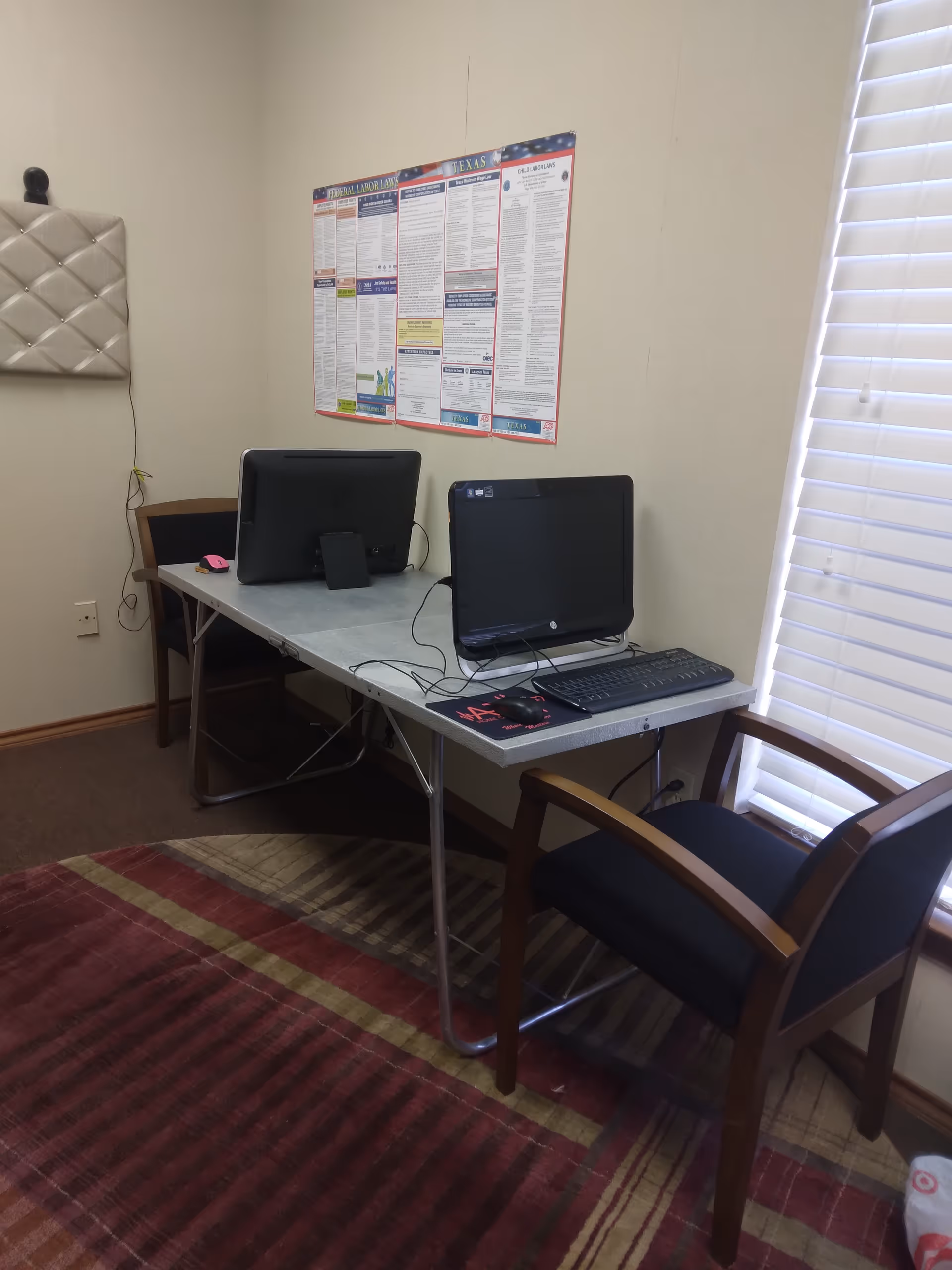 A small bedroom with a desk, two computer monitors, a chair, and blinds.