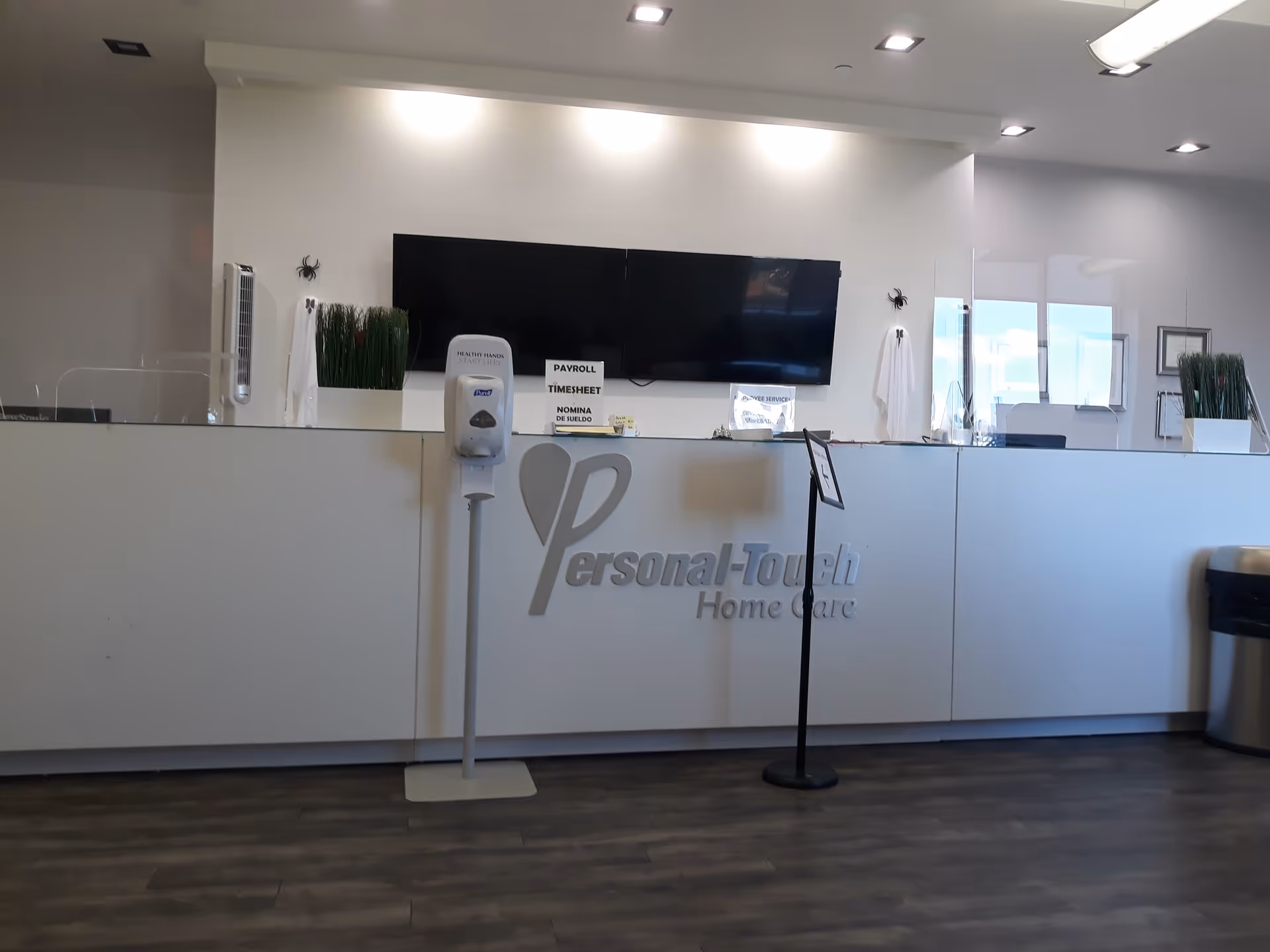Reception desk with Personal-Touch Home Care signage in a modern lobby.