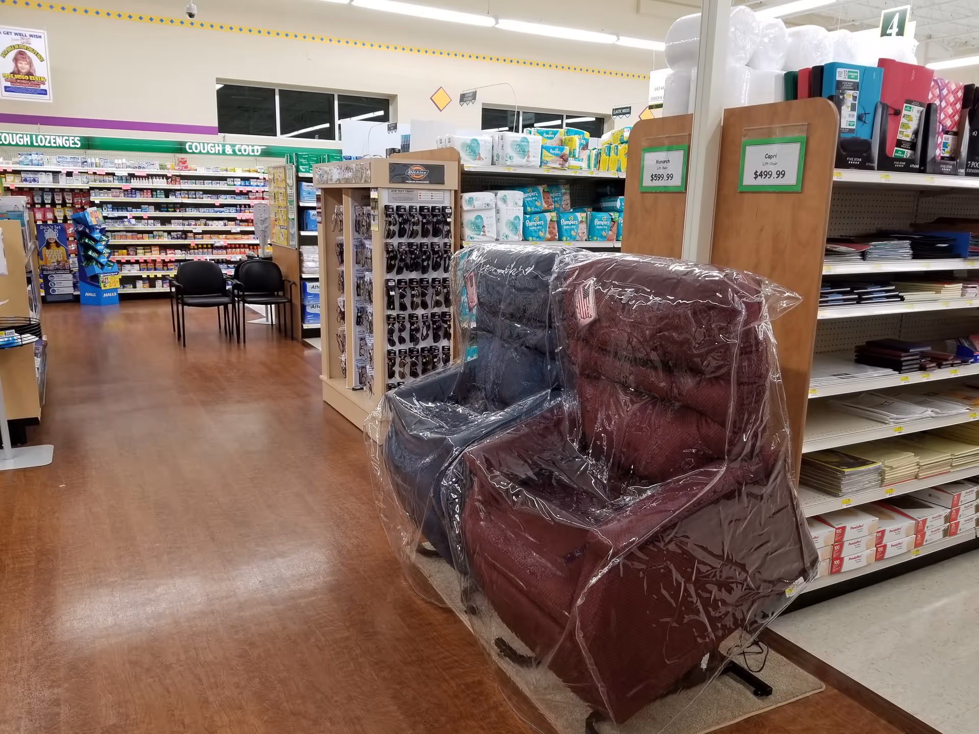 A burgundy recliner wrapped in plastic sits in an aisle of Discount Drug Mart.