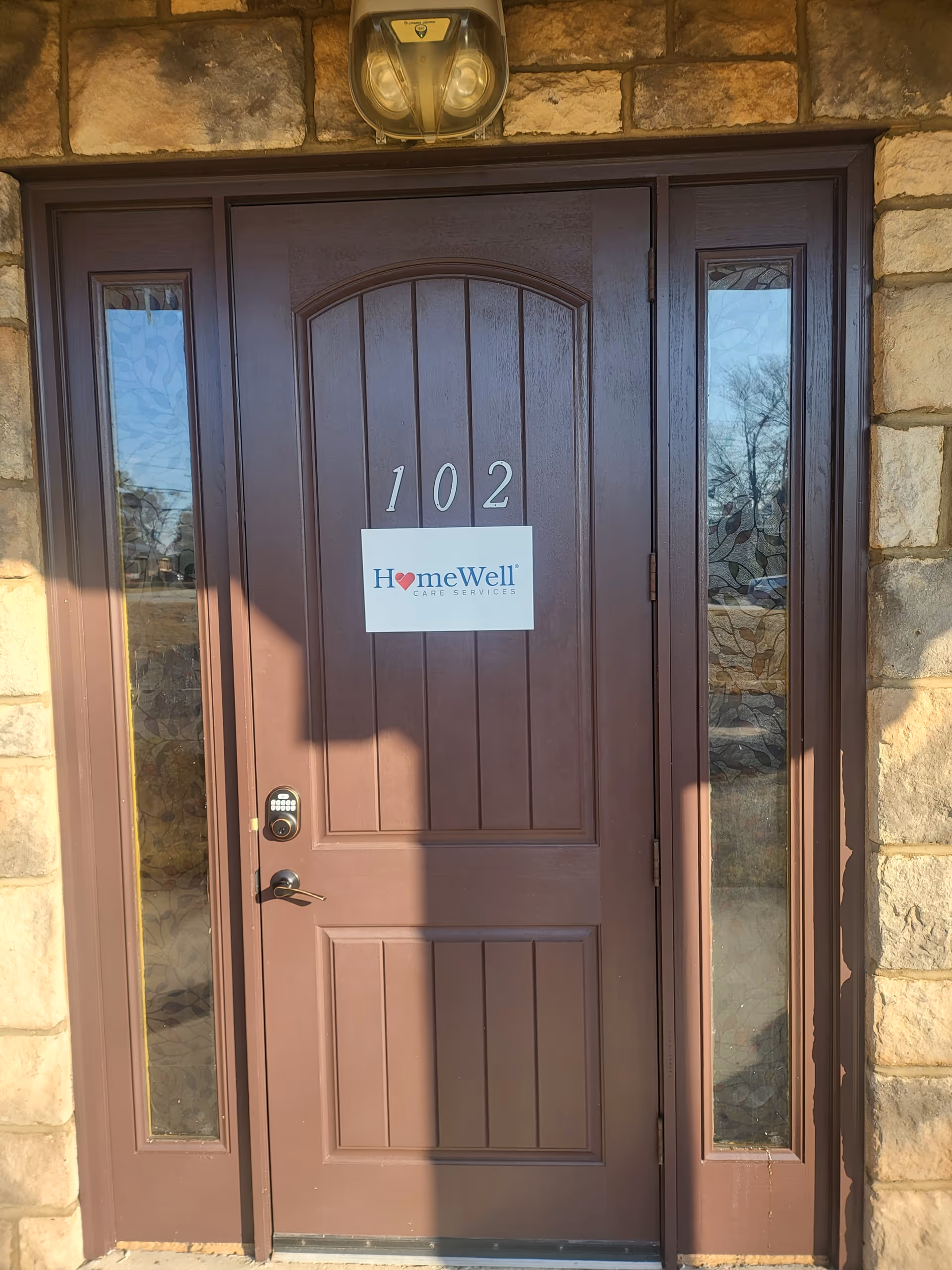 Brown front door with number 102 and HomeWell Care Services sign