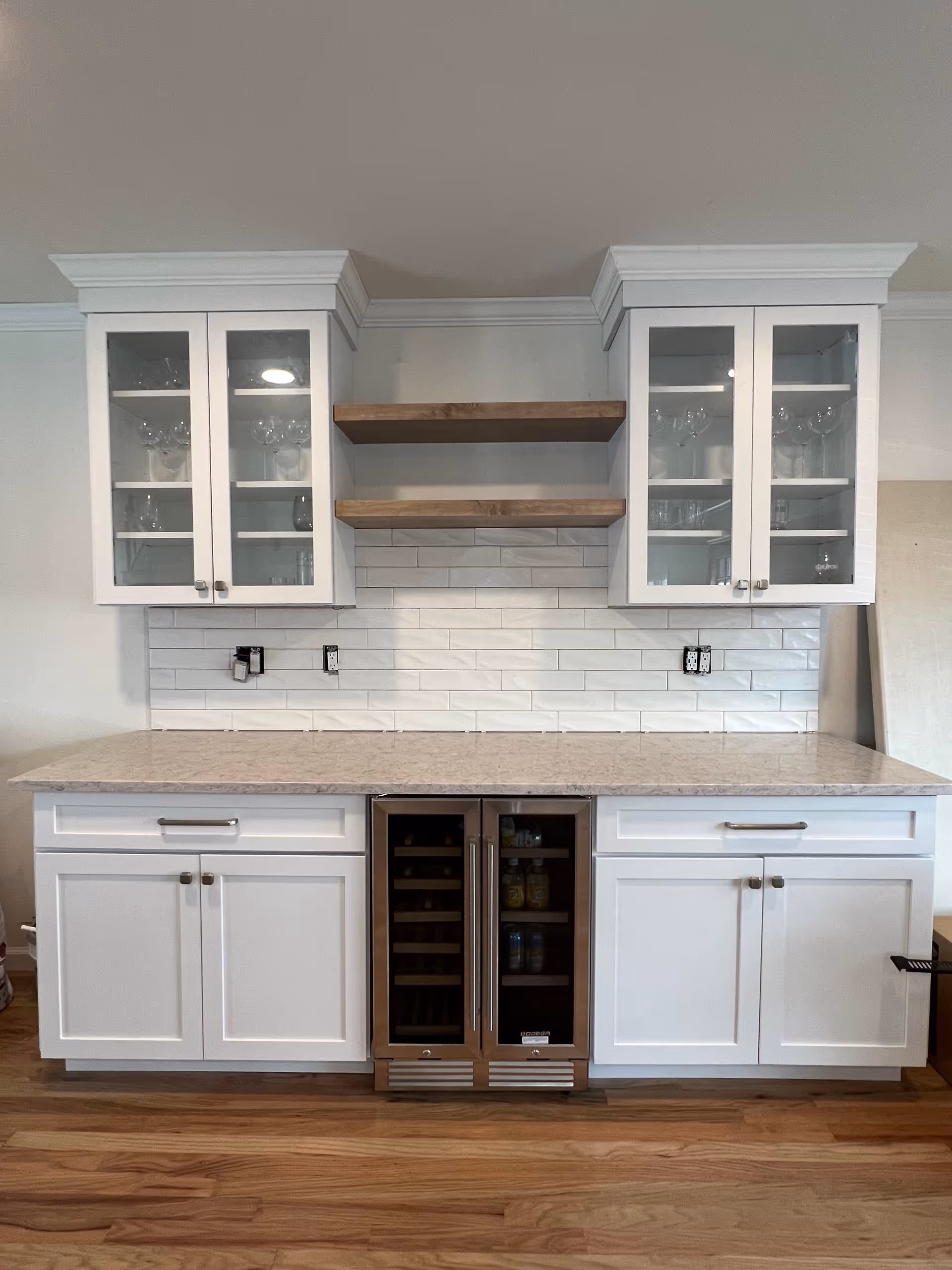 White kitchen cabinets with glass doors, open shelves, and a small wine fridge.