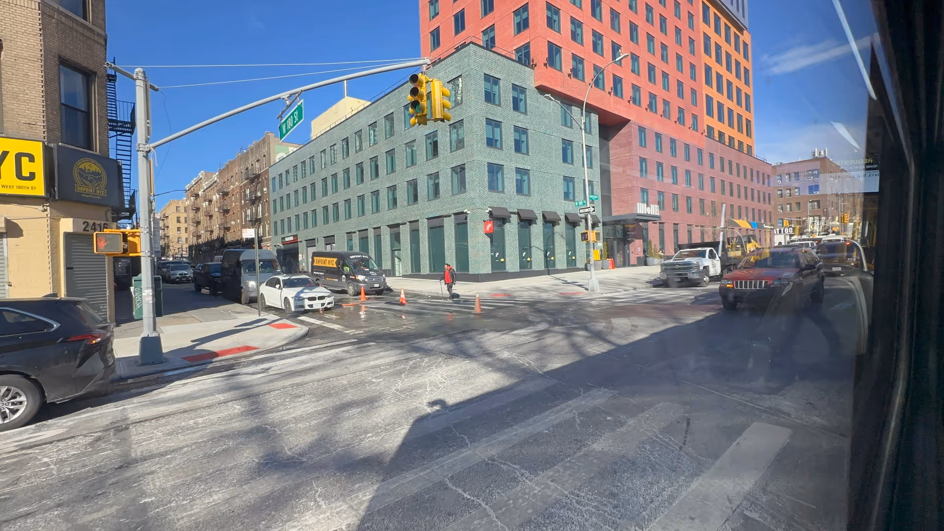 Busy city street with colorful mid-rise buildings and traffic at an intersection.