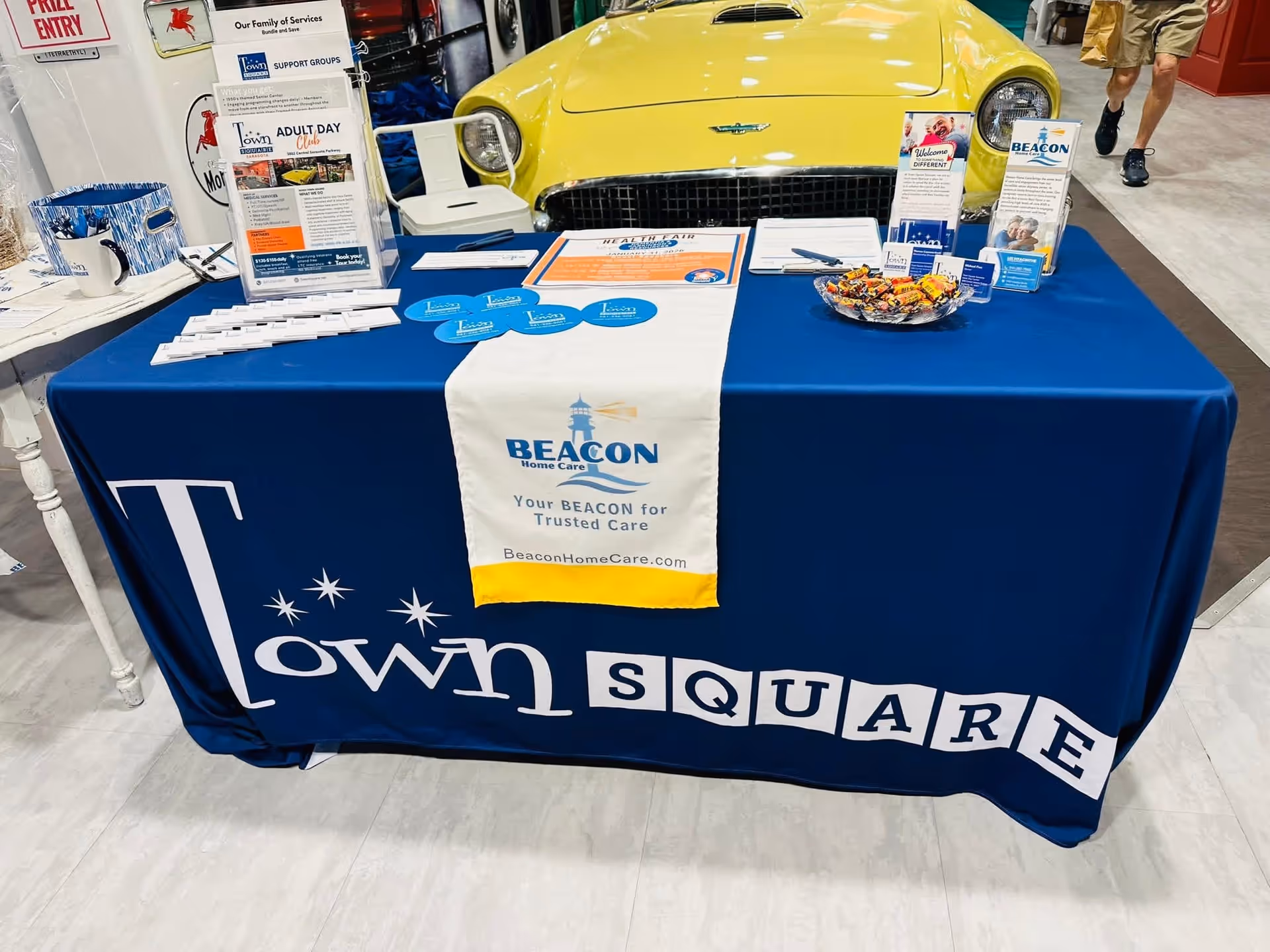 Promotional Beacon Home Care table with blue cloth and yellow car behind.