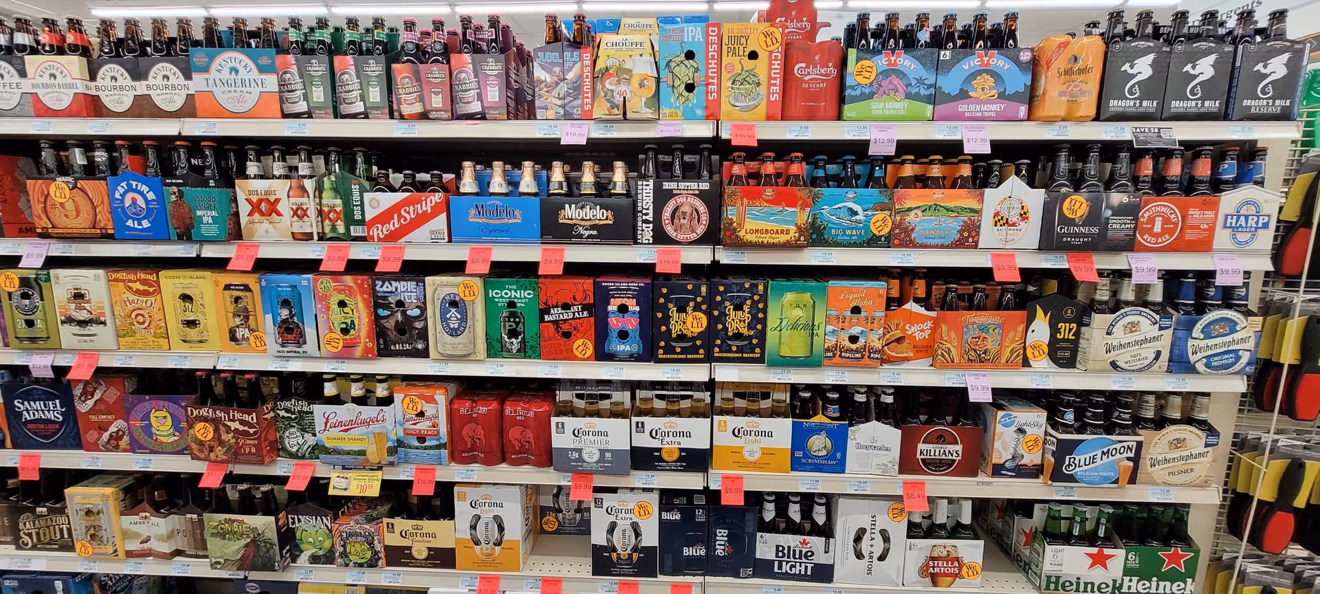 Colorful beer packs line store shelves in a grocery aisle.