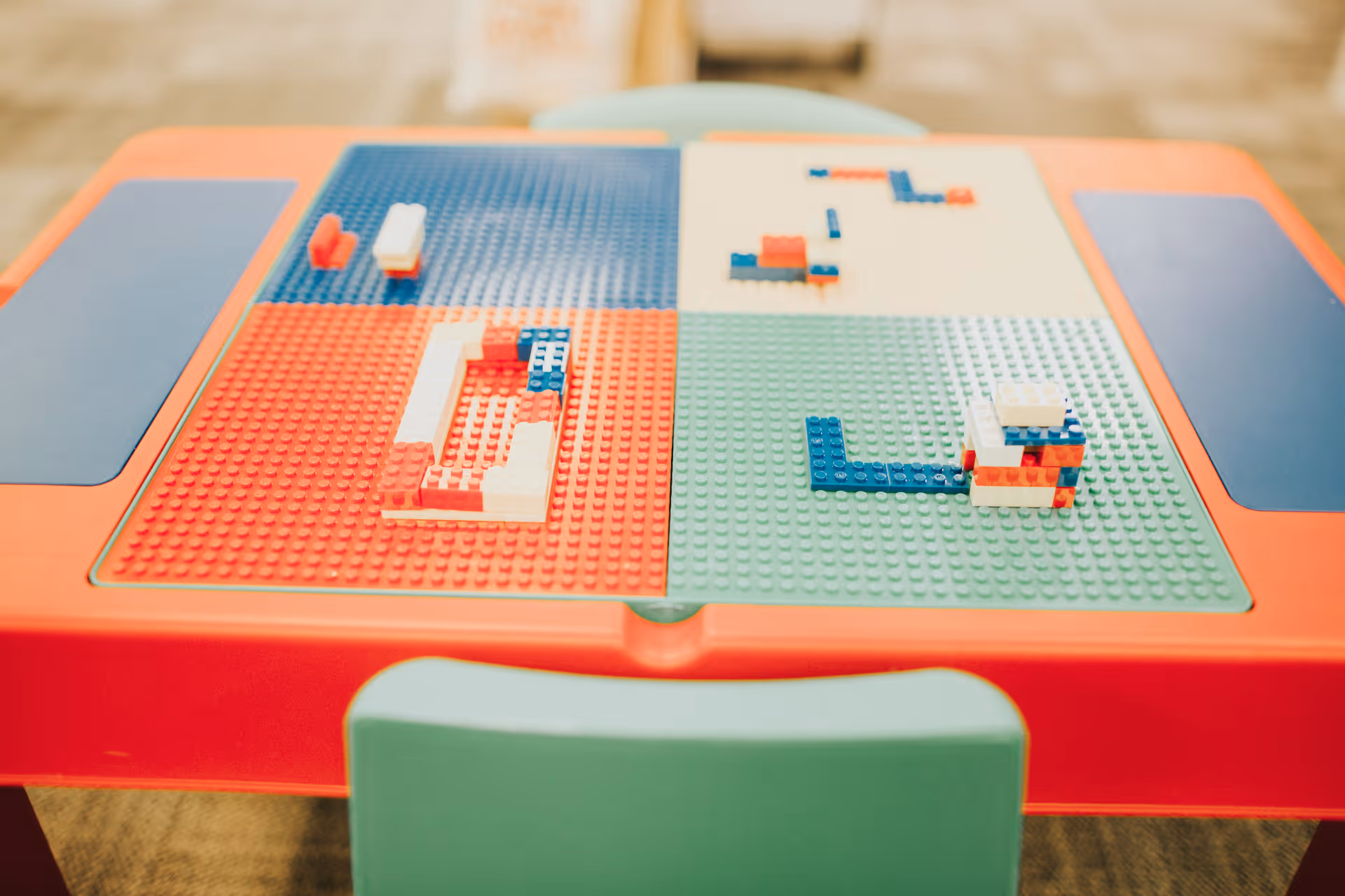 Colorful LEGO bricks arranged on a multicolored play table inside an indoor facility.