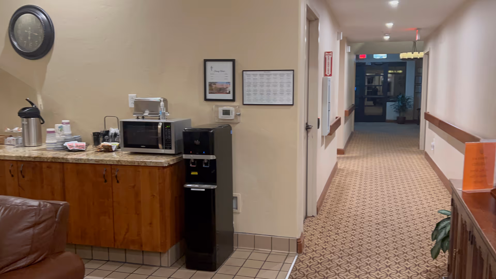 Interior hallway of a senior living facility featuring a coffee station and doorway to other rooms.