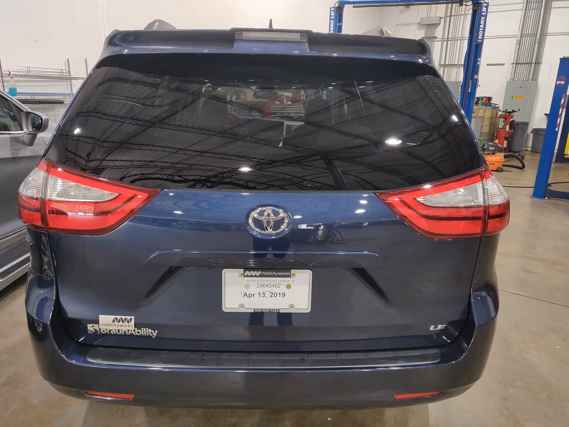 Rear view of a blue Toyota SUV in a vehicle service workshop.
