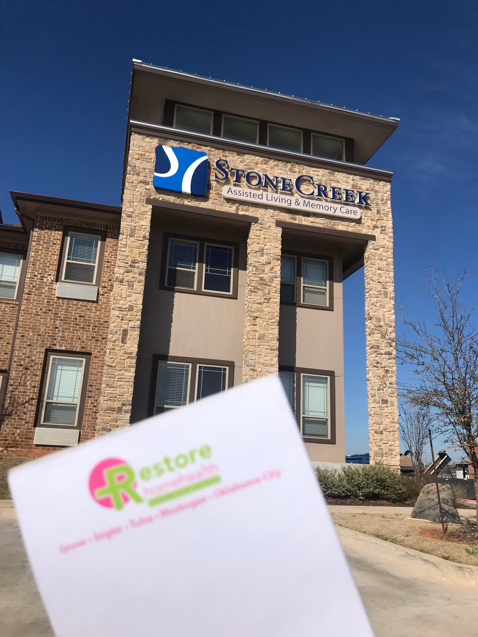 StoneCreek assisted living building exterior with sign under a blue sky.