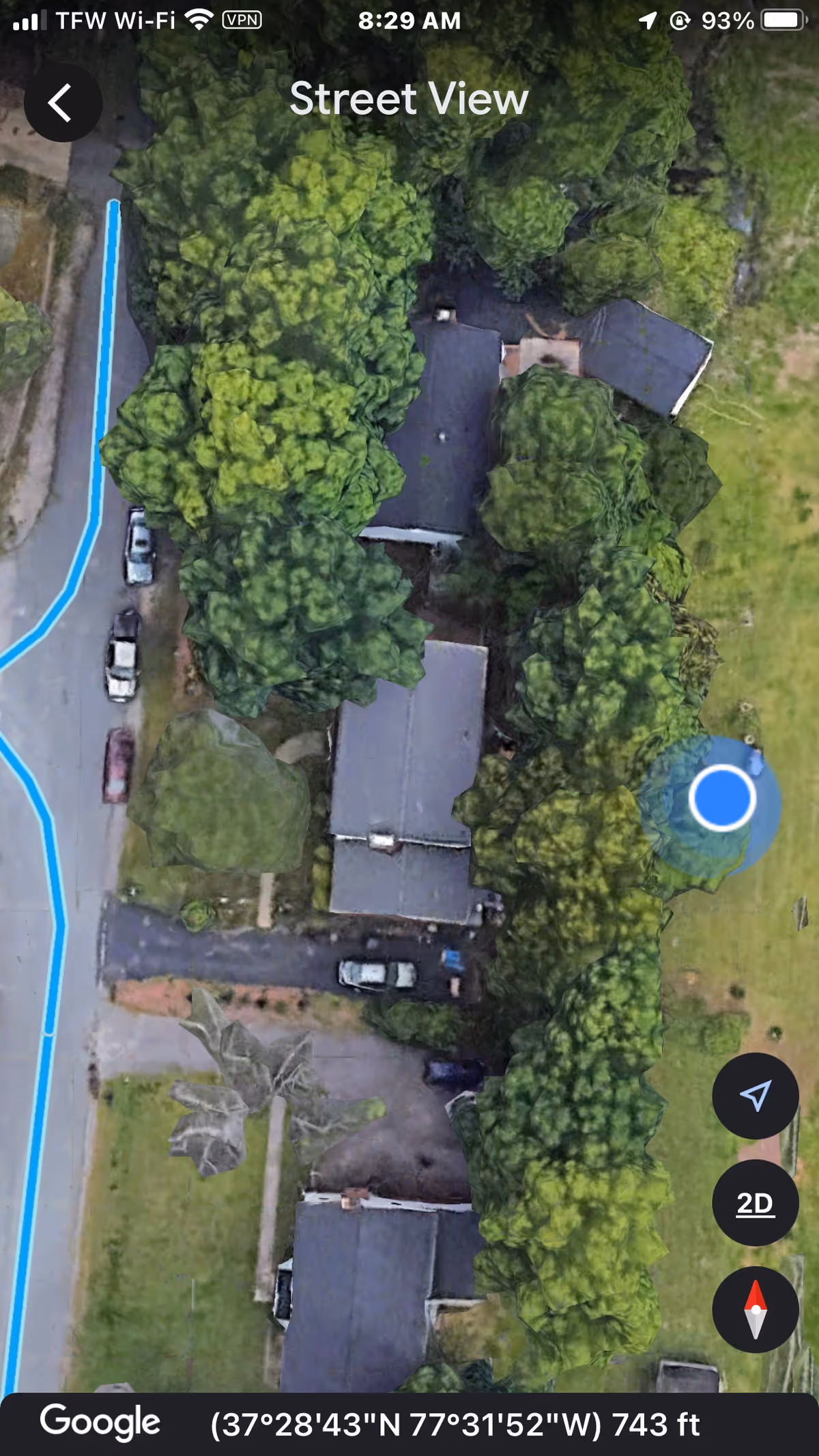 Aerial view of a tree-filled facility with multiple buildings and parked cars.