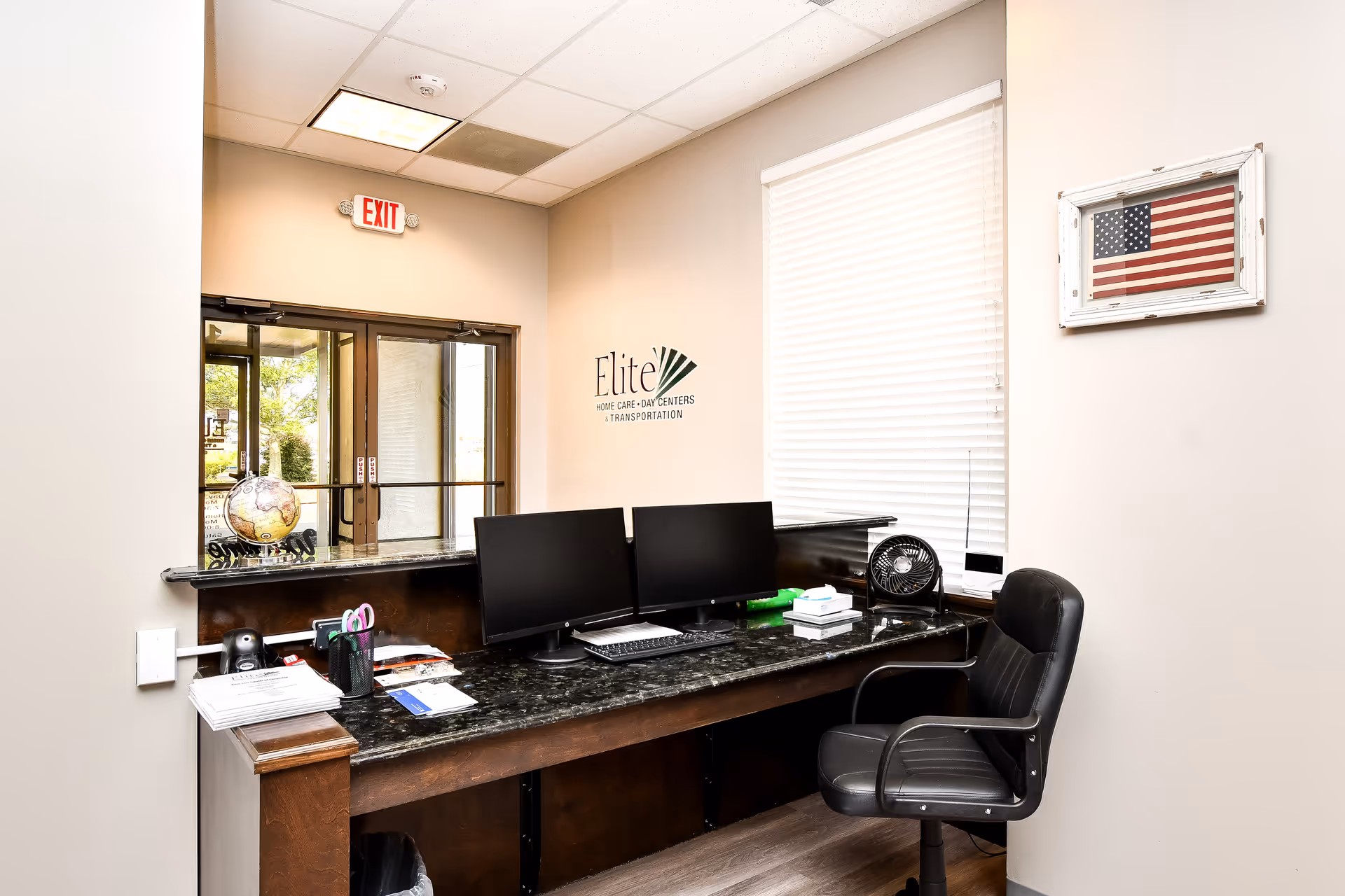 Reception desk with two computer monitors in Elite Home Care office.