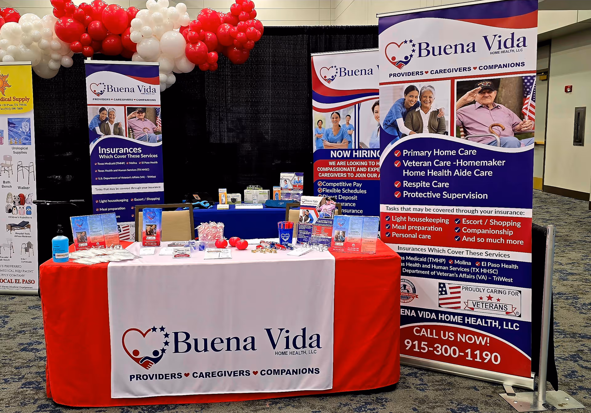 Indoor expo booth for Buena Vida Home Health with banners, balloons, and a table.