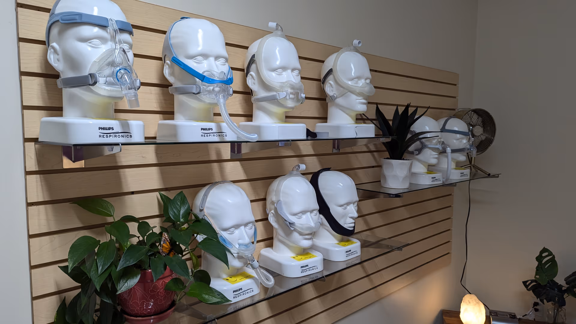 Rows of CPAP mask mannequins mounted on a slat wall in a medical equipment display.