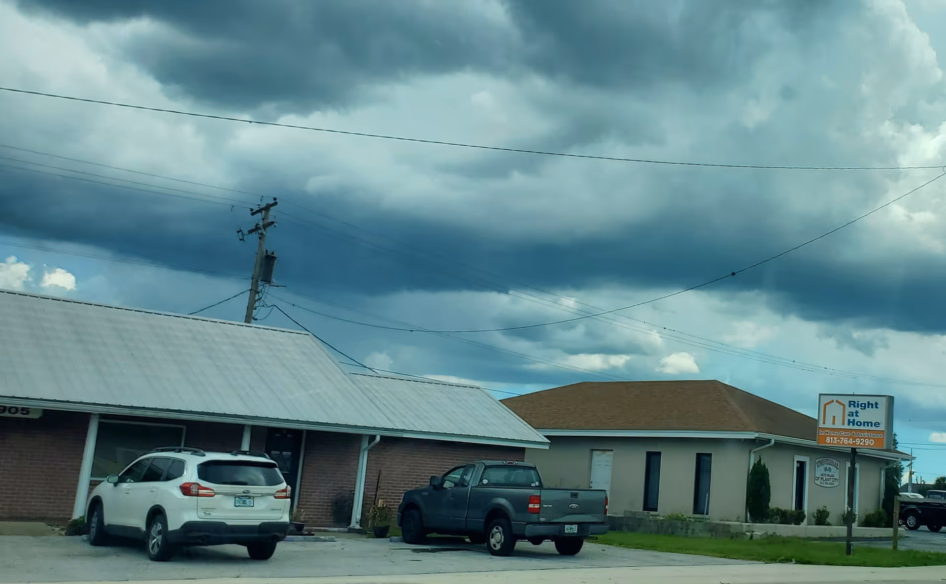 Exterior view of Right at Home senior living facility with parked cars under cloudy sky.