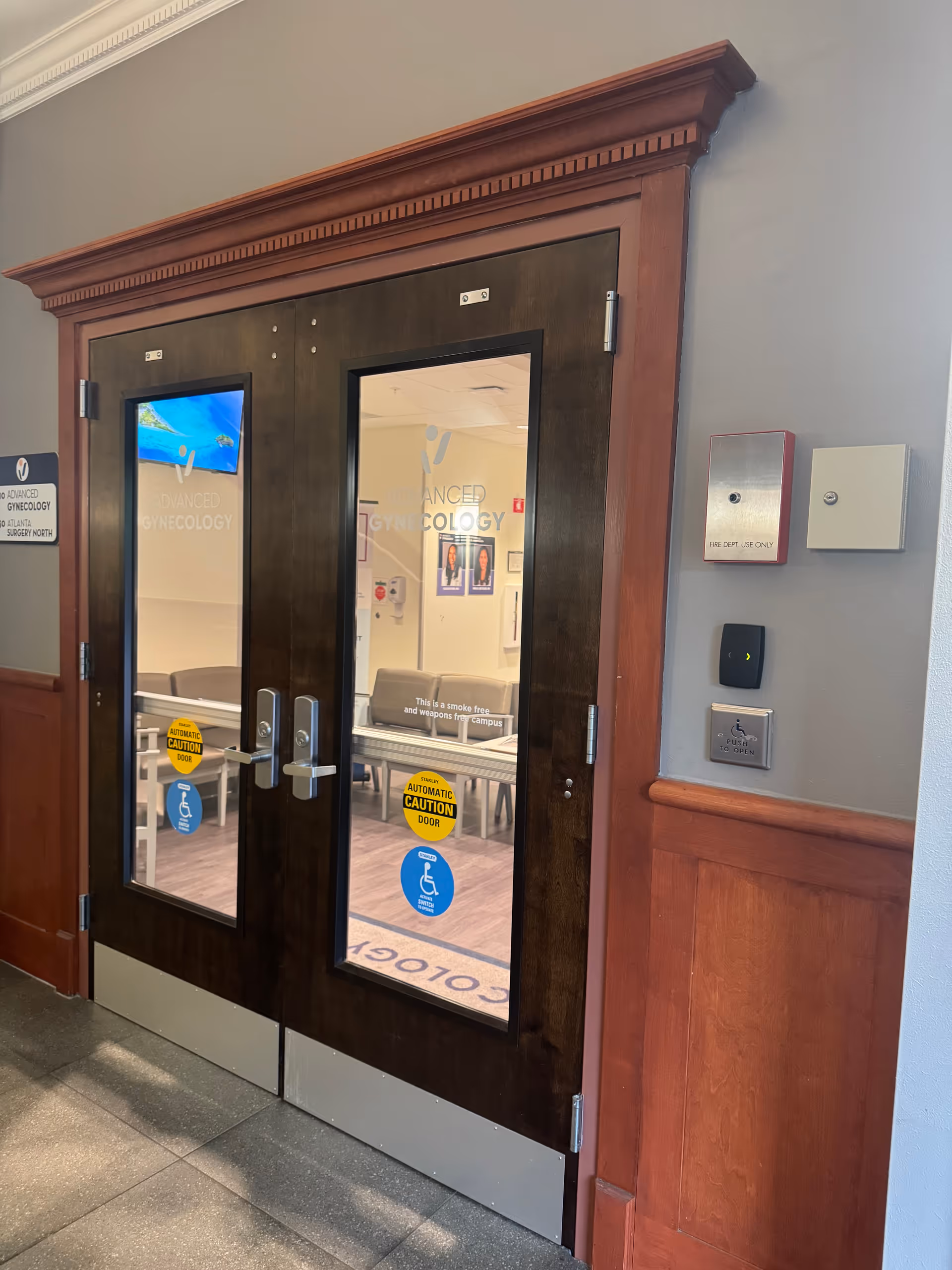 Double wooden doors with glass panels open into an Advanced Gynecology clinic hallway.