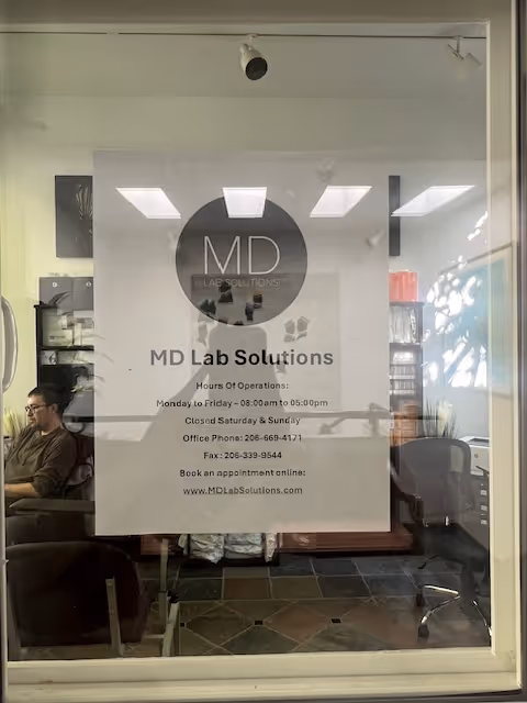 Interior office through glass door featuring MD Lab Solutions sign and a seated man.