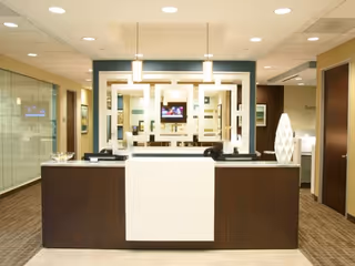 Modern reception desk in a senior living facility lobby with geometric wall decor.