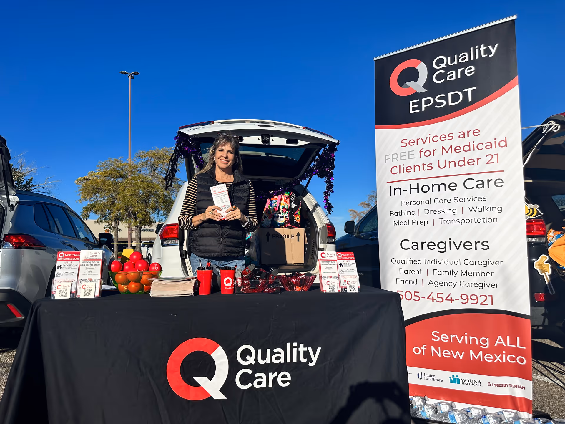 Outdoor Quality Care booth with a woman presenting brochures at a table
