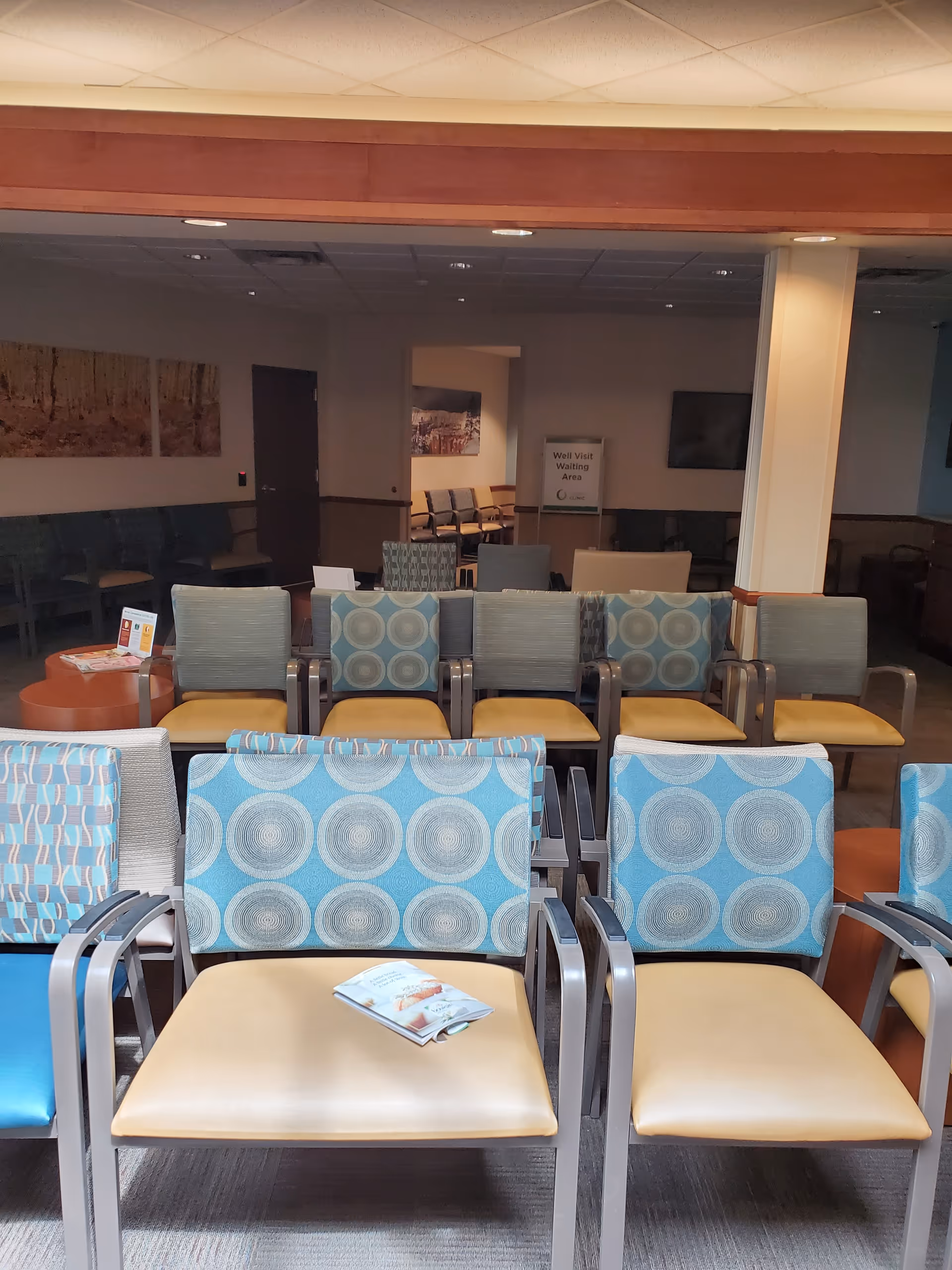 Interior waiting area with rows of blue patterned chairs and a sign in the background