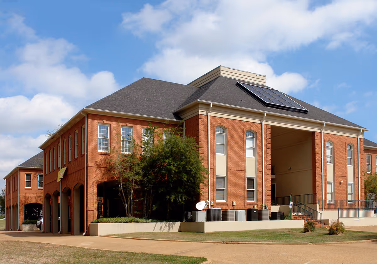Brick senior living facility exterior with solar panels and a covered entrance.