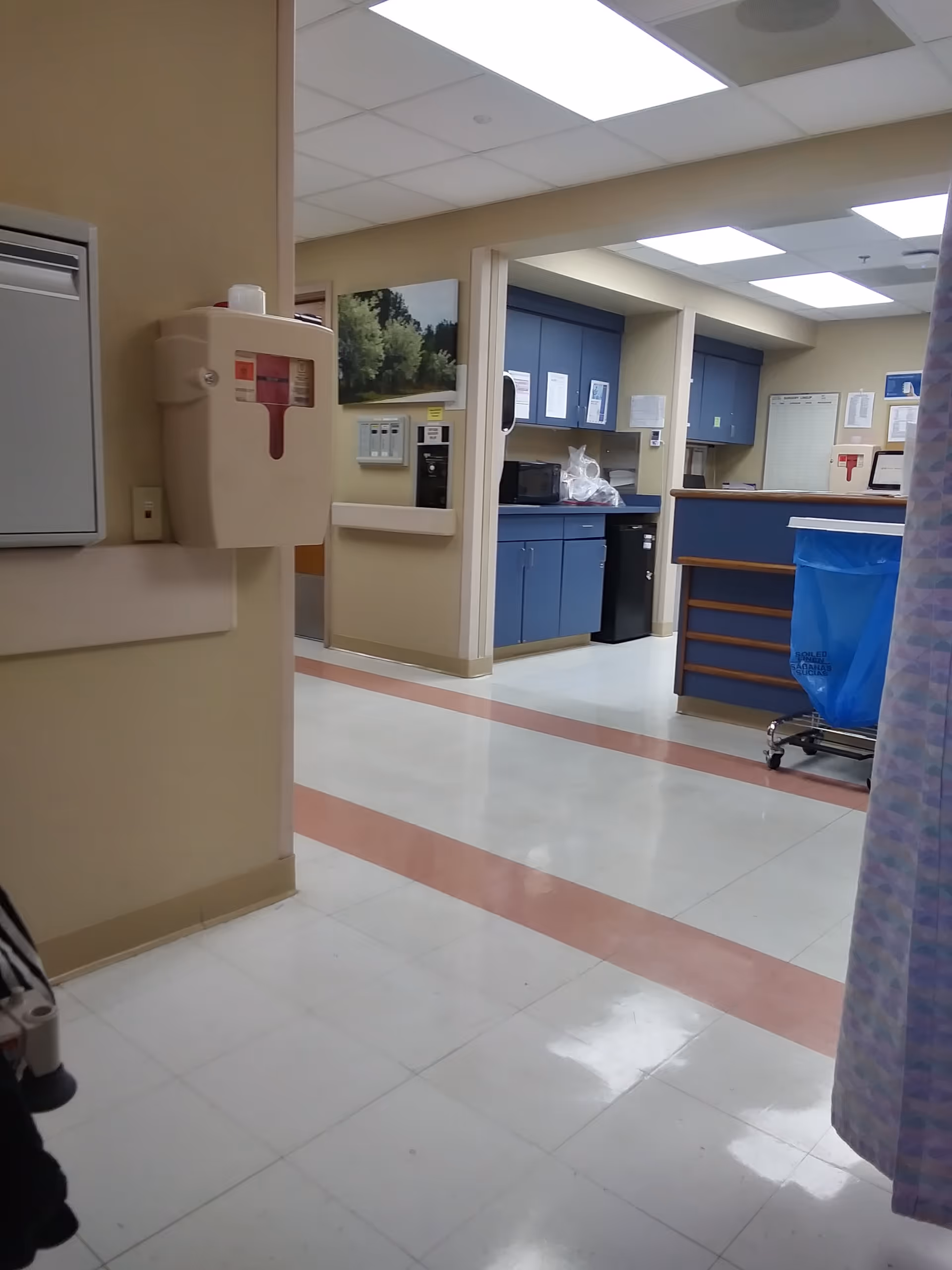 Hospital hallway interior with blue cabinets, counter, and medical equipment.