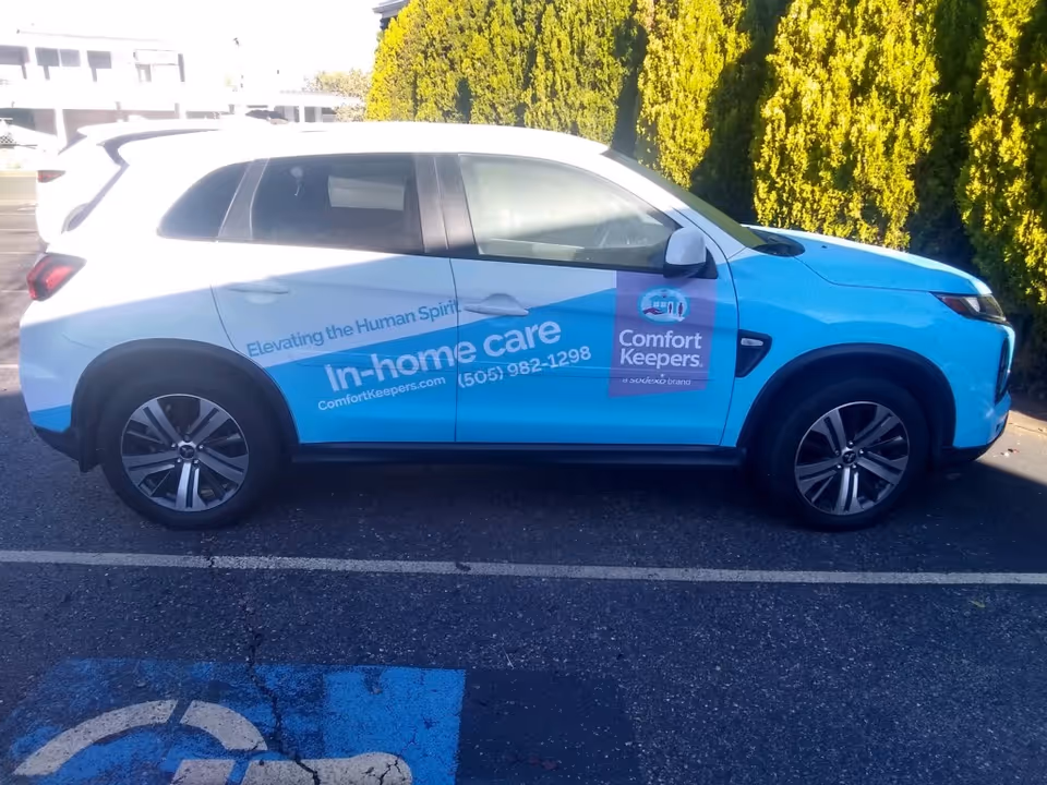 Blue and white Comfort Keepers in-home care vehicle parked in a lot