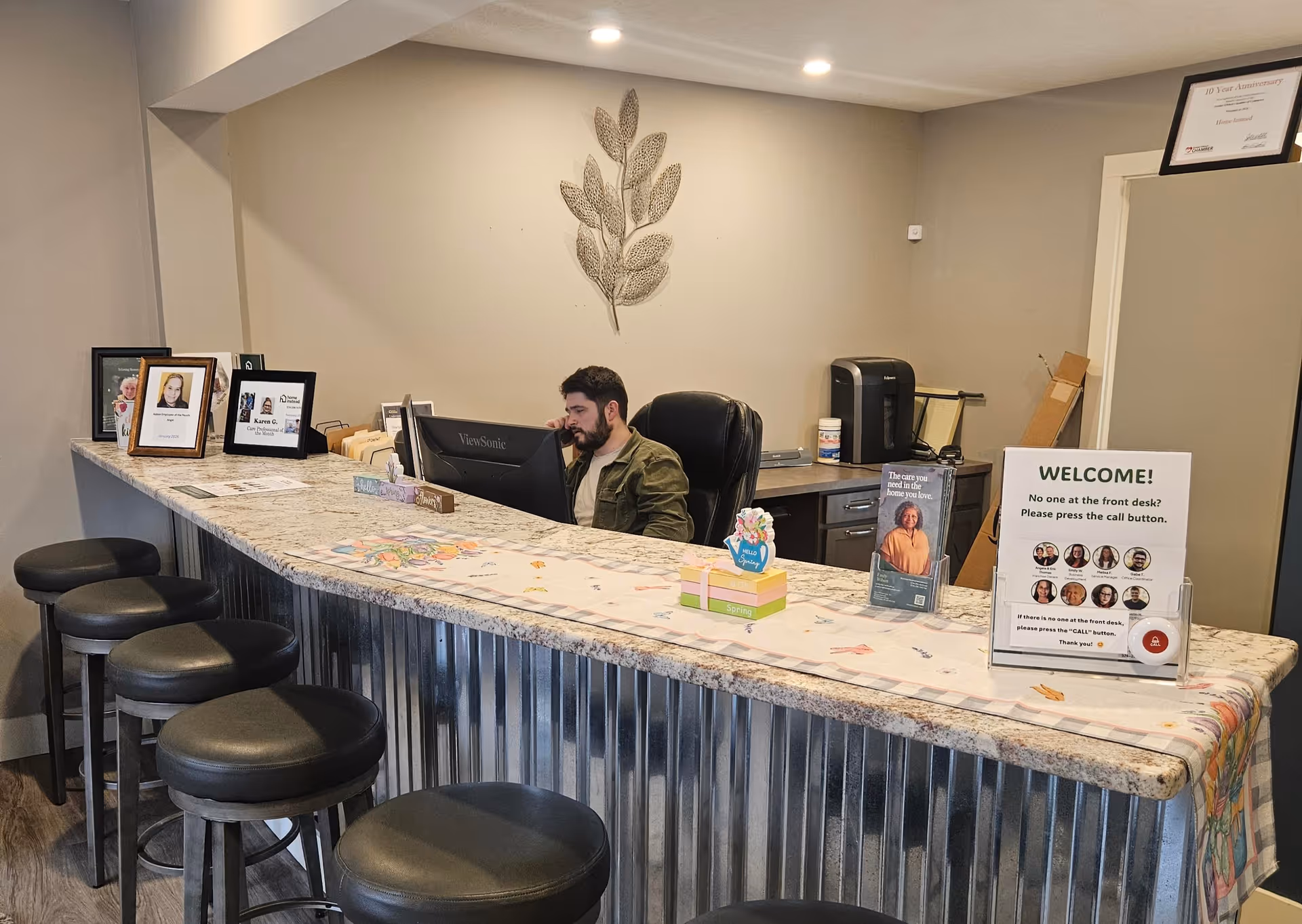 Staff member sits at a computer behind a marble reception desk in a lobby.