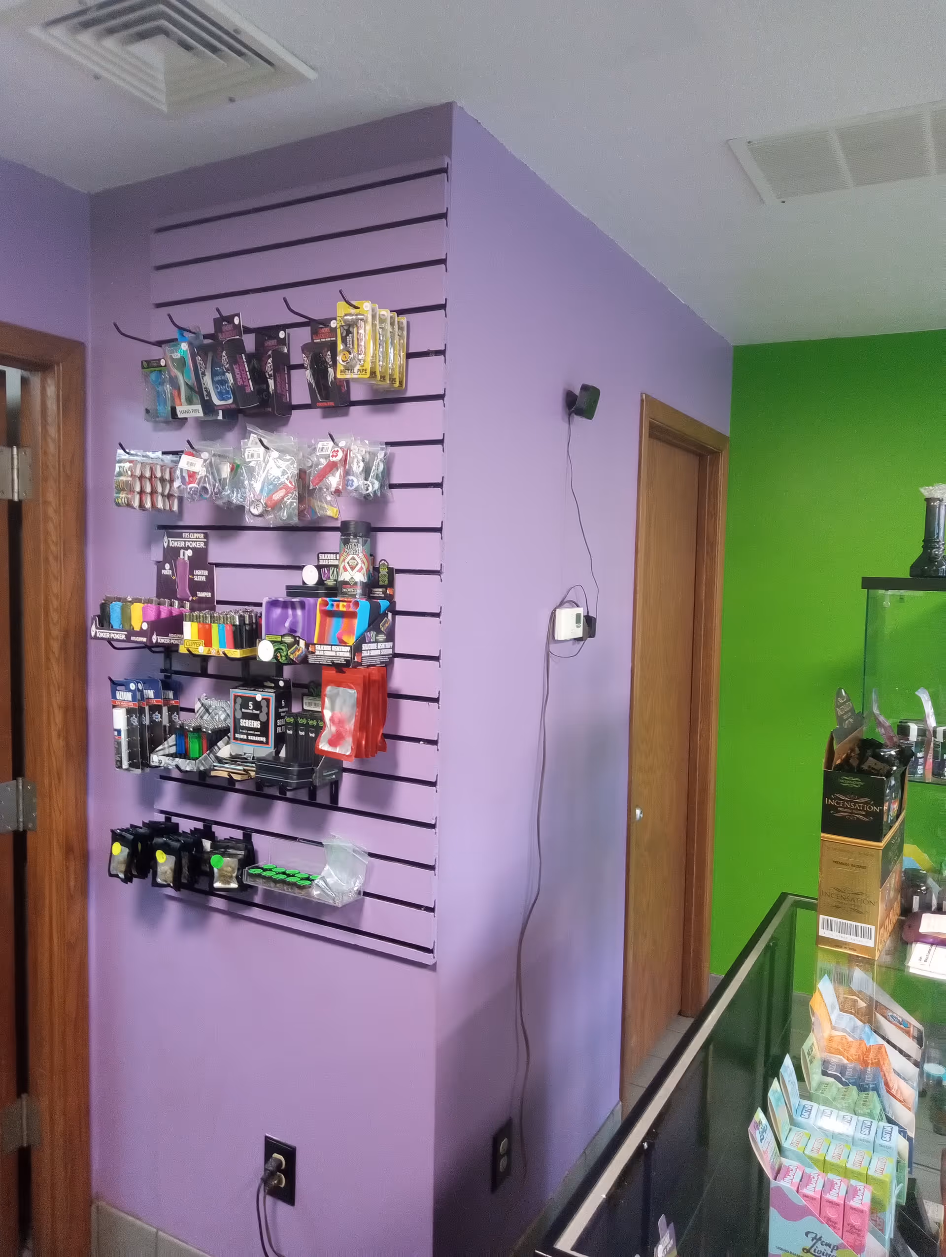 Interior shop area with purple walls and a slatwall displaying assorted small items.