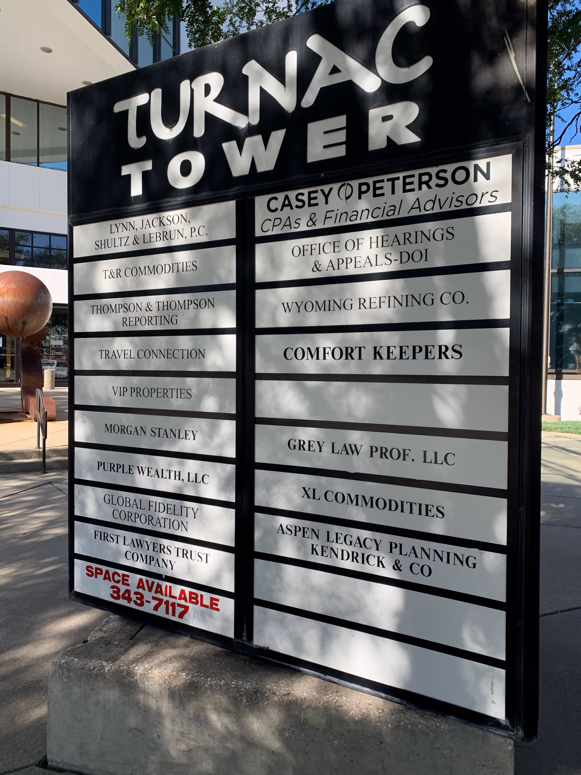 Large outdoor signboard listing tenants, including Comfort Keepers, on a modern building front.