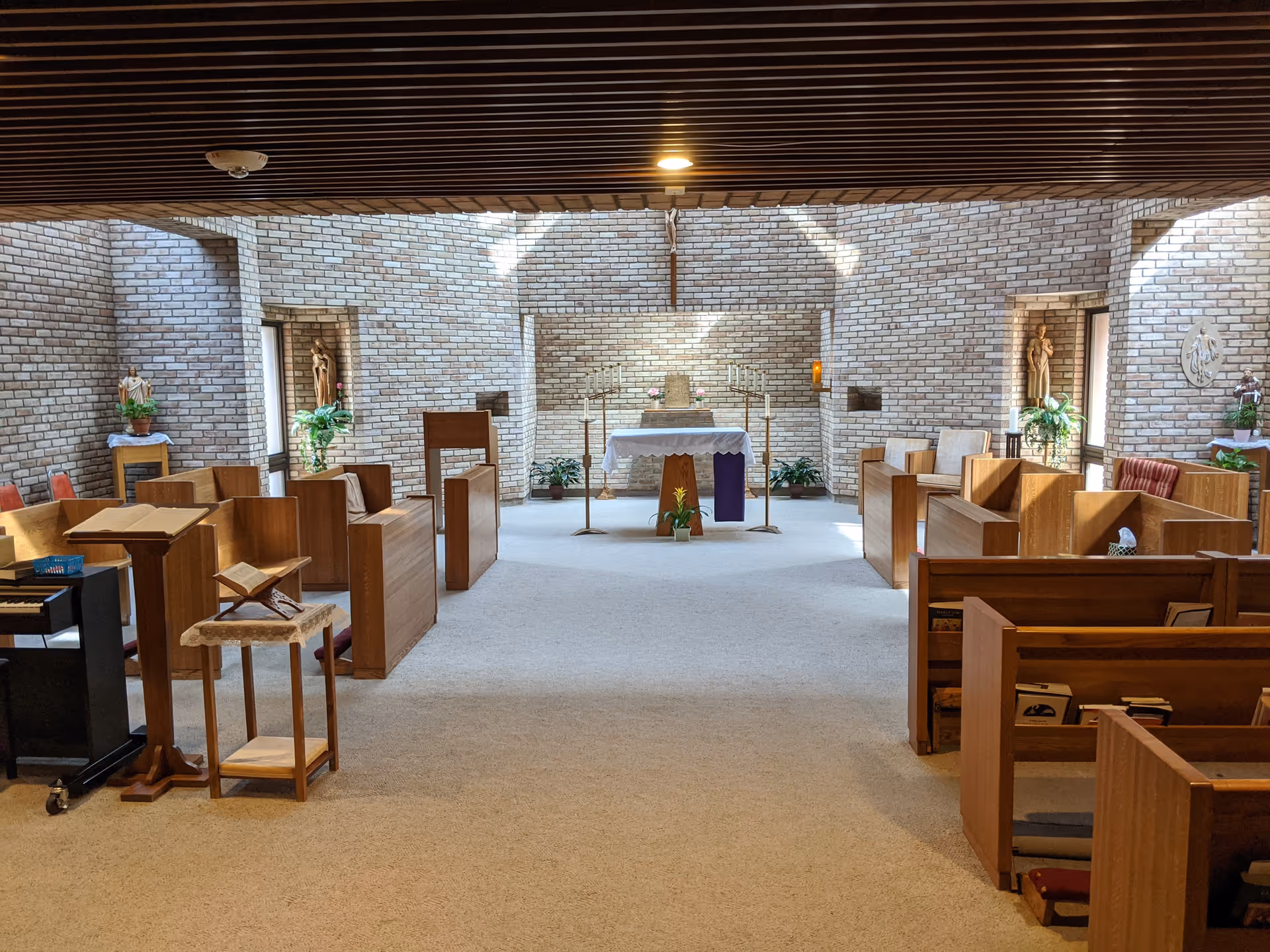 Chapel interior with wooden pews, brick walls, and an altar at the front