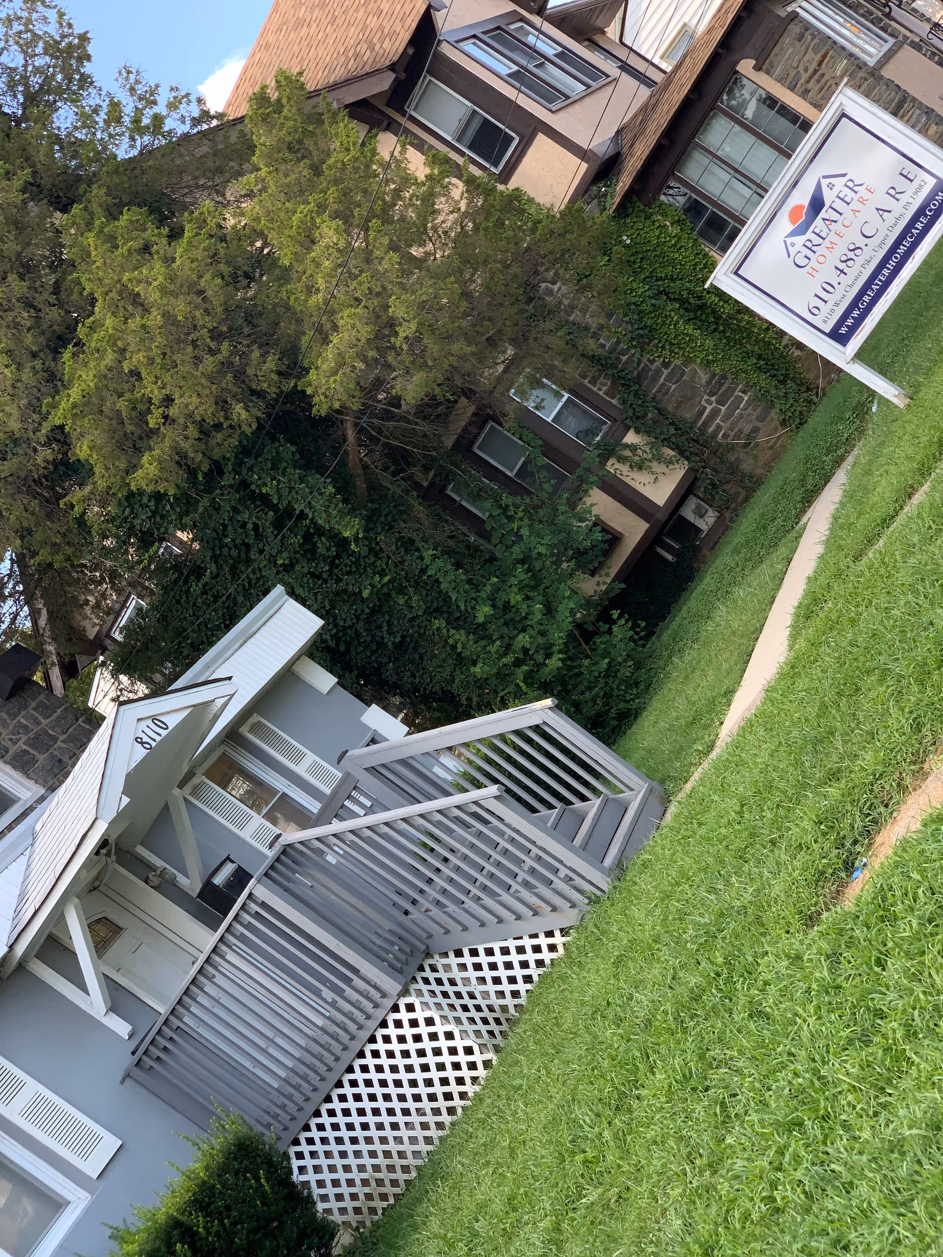 Exterior view of a multi-story senior care building with a grassy lawn and sign.
