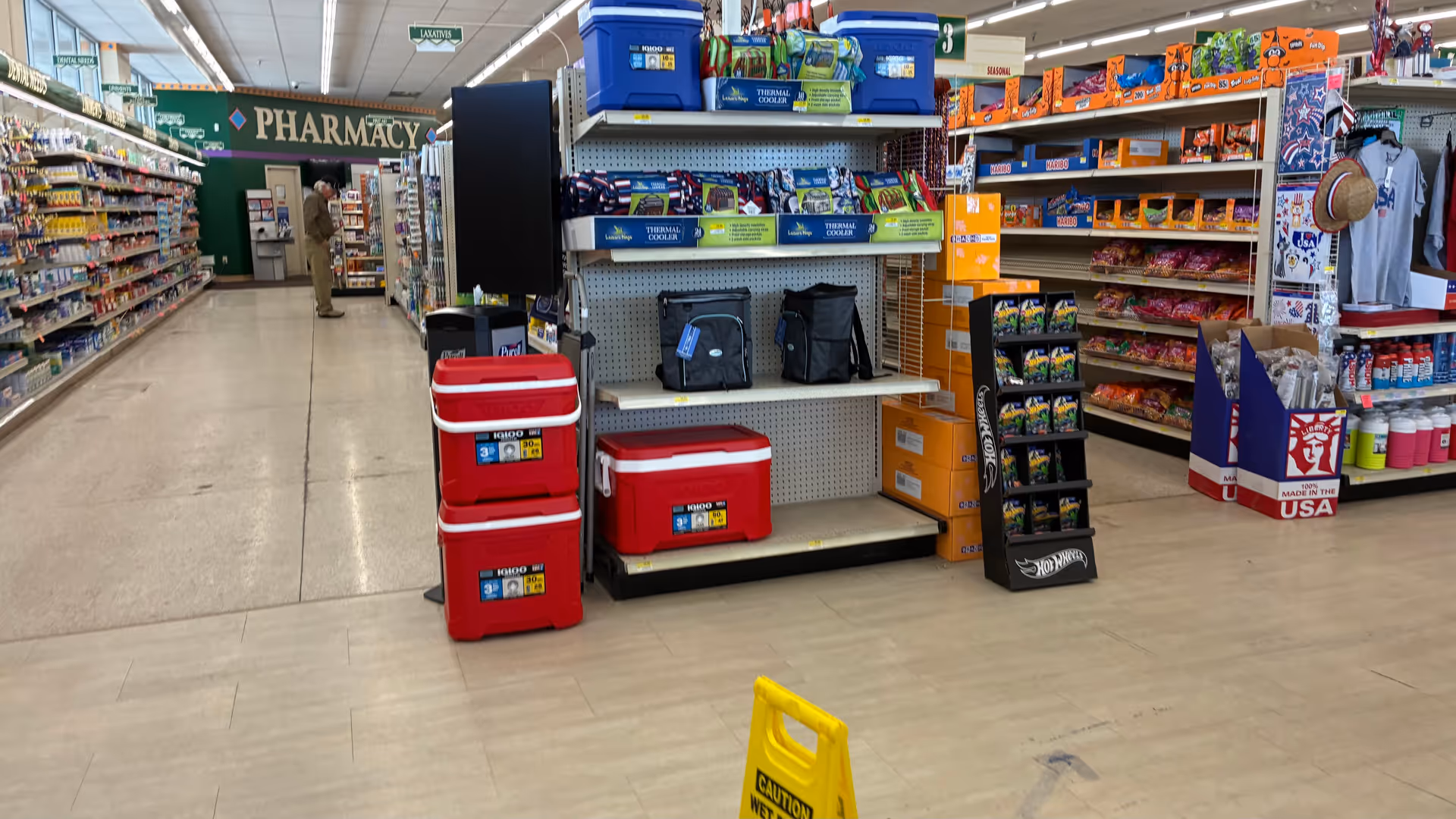 Wide aisle inside Discount Drug Mart with shelves, red coolers, and shoppers.