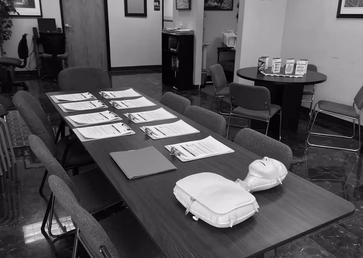 Conference room with a long table, clipboards, and a CPR training mannequin.