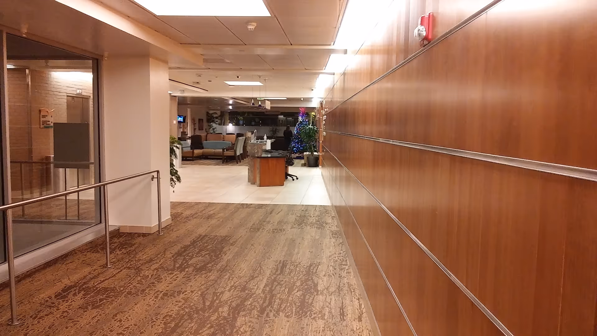 A long interior corridor with wood-paneled right wall leading to a seating area.