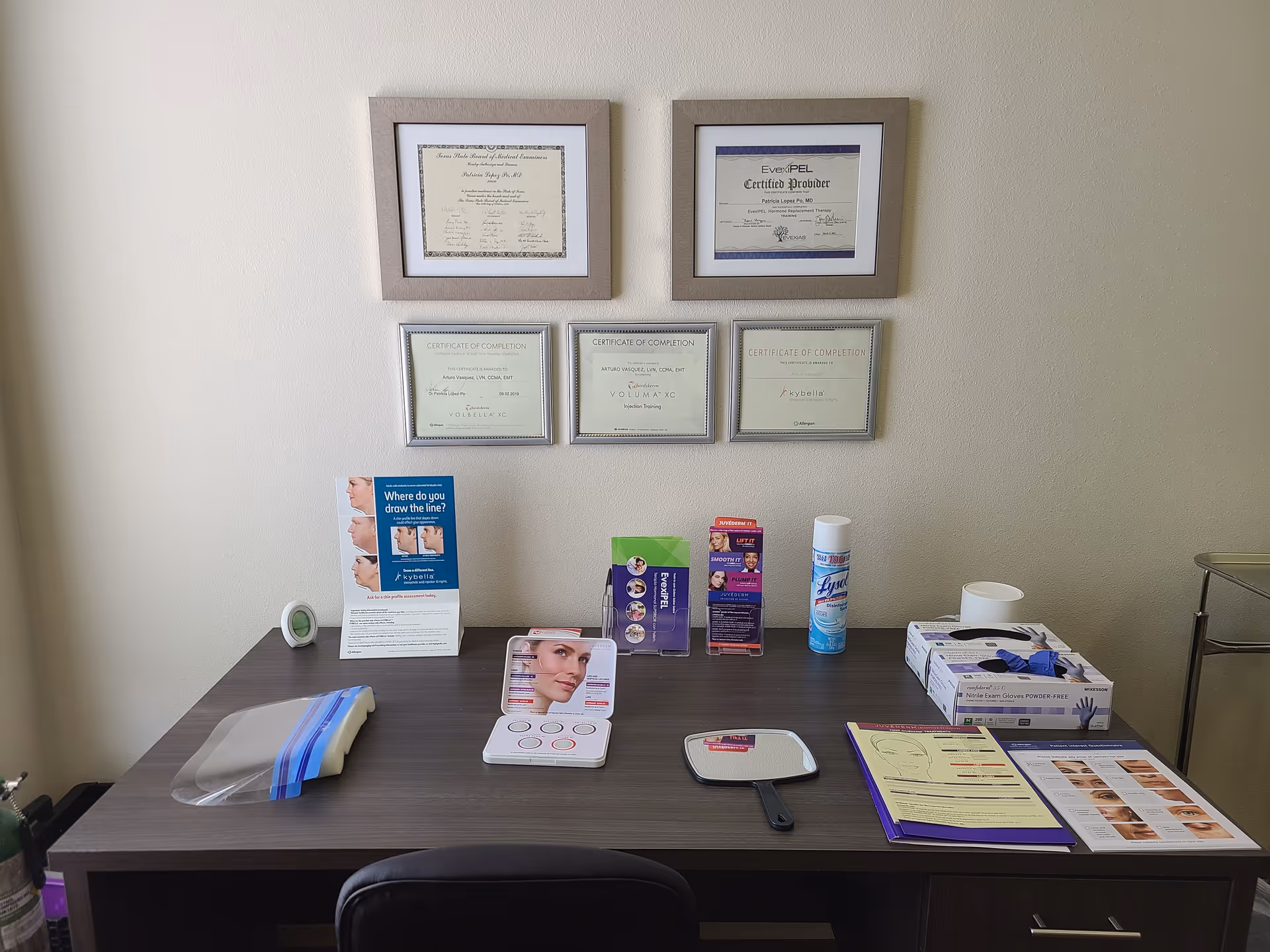 Desk with brochures and framed certificates on the wall in a reception area.