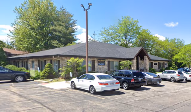 Single-story senior living facility with stone exterior and a parking lot in front.