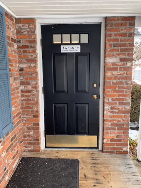 Black front door with Premier Home Health Care Services sign on brick exterior.