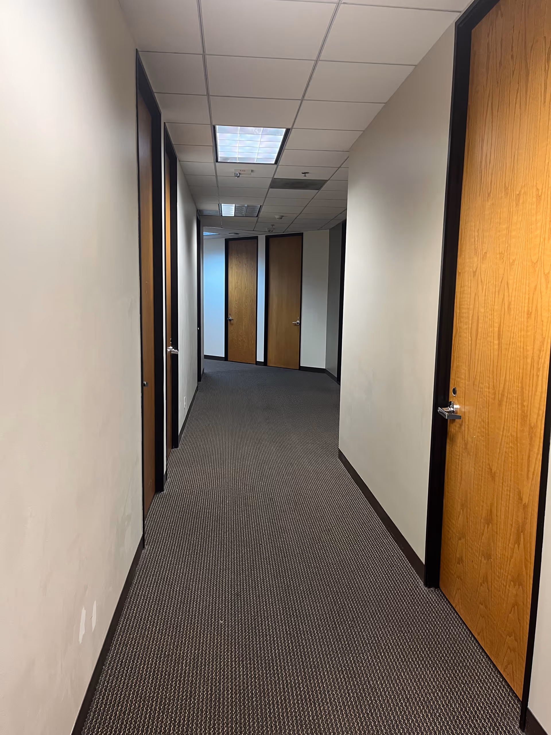 Narrow hallway in a senior living facility with wooden doors along both walls.