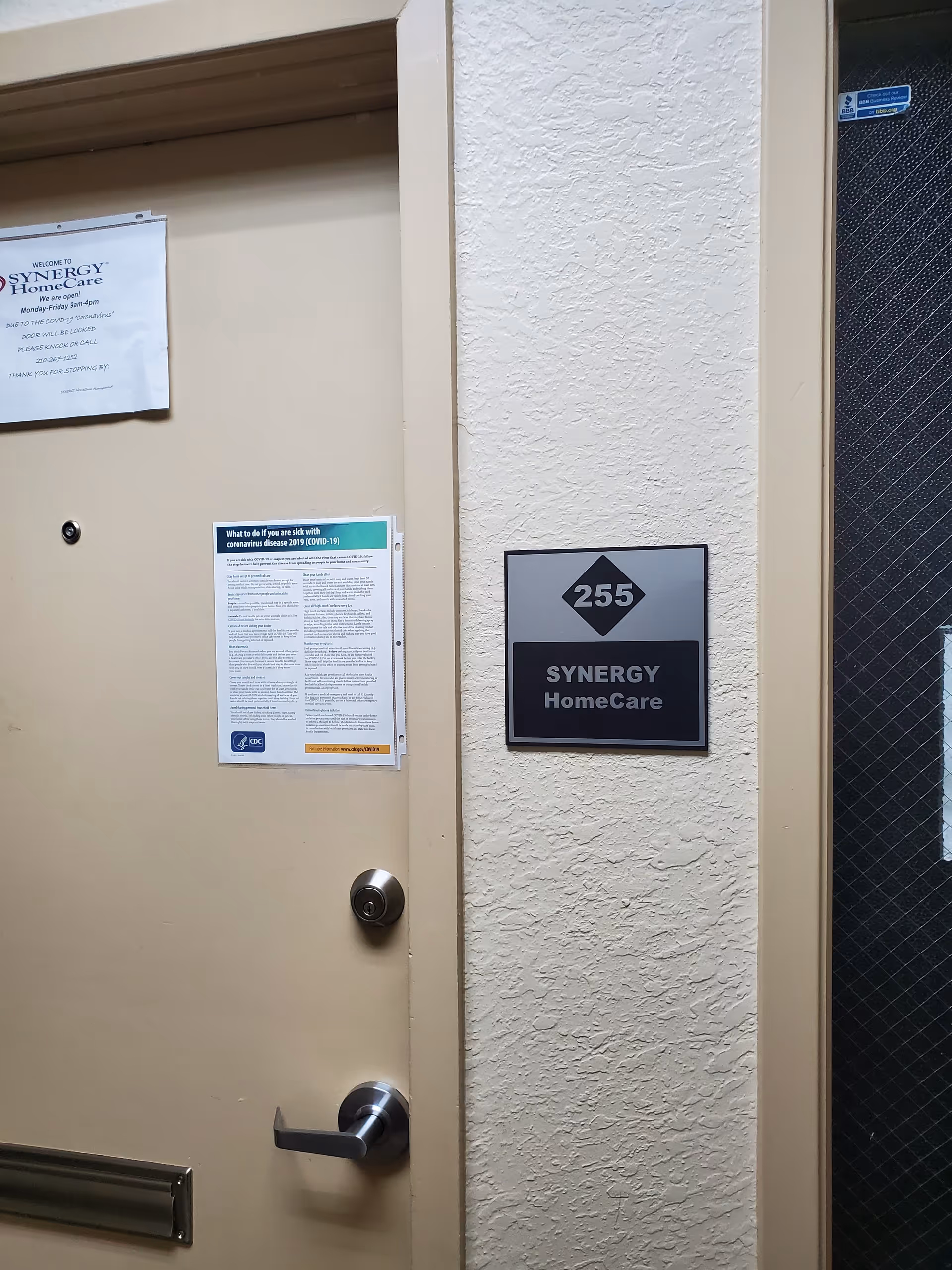 Exterior door with Synergy HomeCare sign and 255 plaque on textured wall
