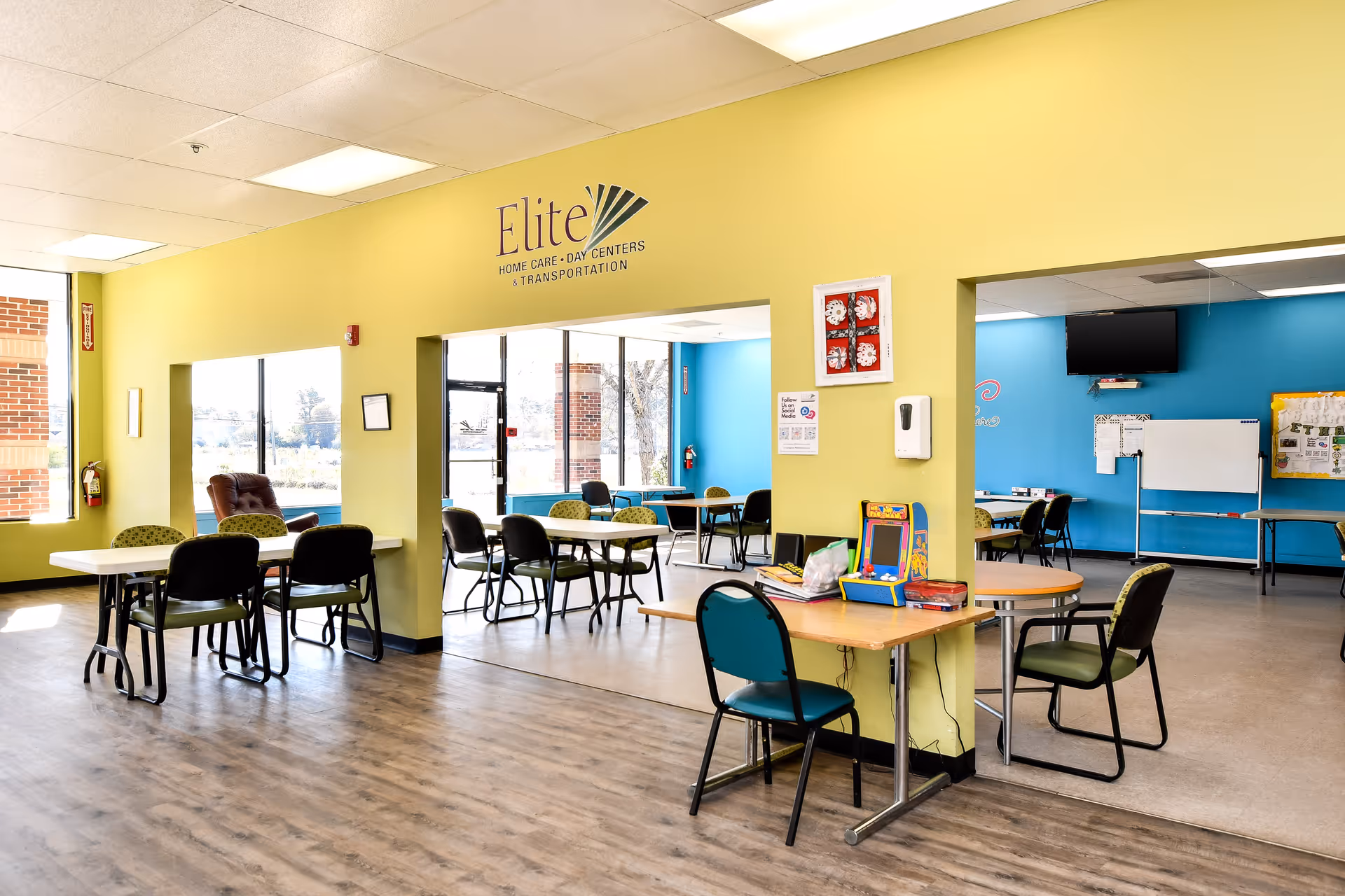 Bright yellow-walled senior facility dining area with tables and chairs