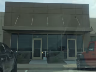 Front exterior of a modern facility with glass doors and two entrances.