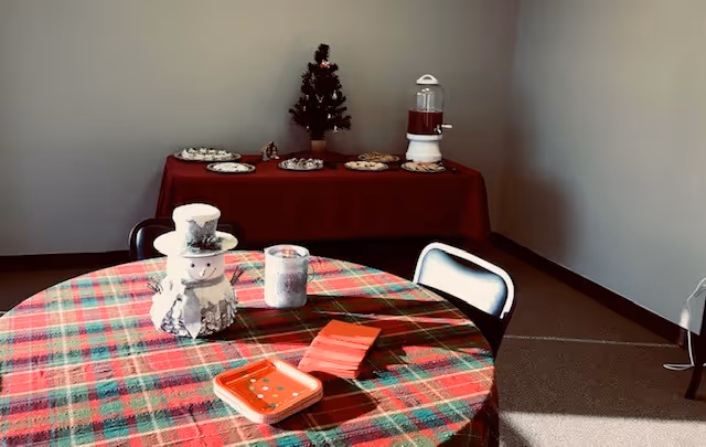 Holiday dining area featuring a round plaid table, snowman centerpiece, and dessert table.