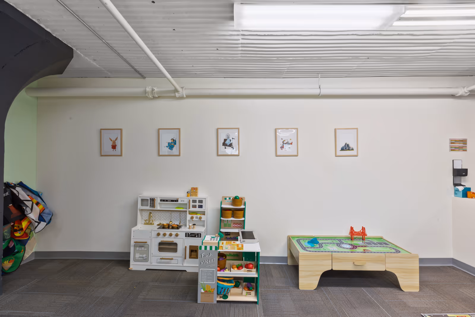 An indoor children's play corner in a senior facility with a toy kitchen and activity table.