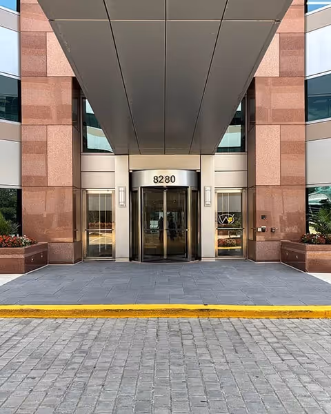 Modern building entrance with glass doors and a covered drop-off area at the main entrance.