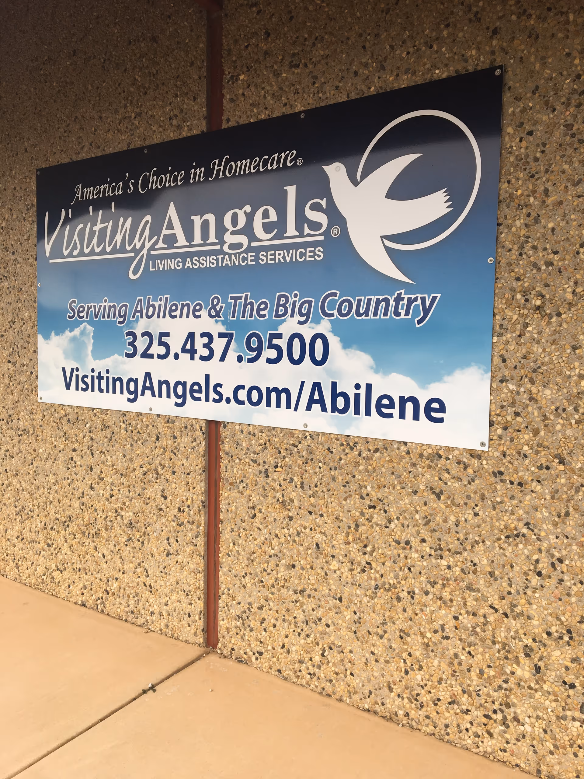 Large Visiting Angels sign on speckled exterior wall advertising home care services.
