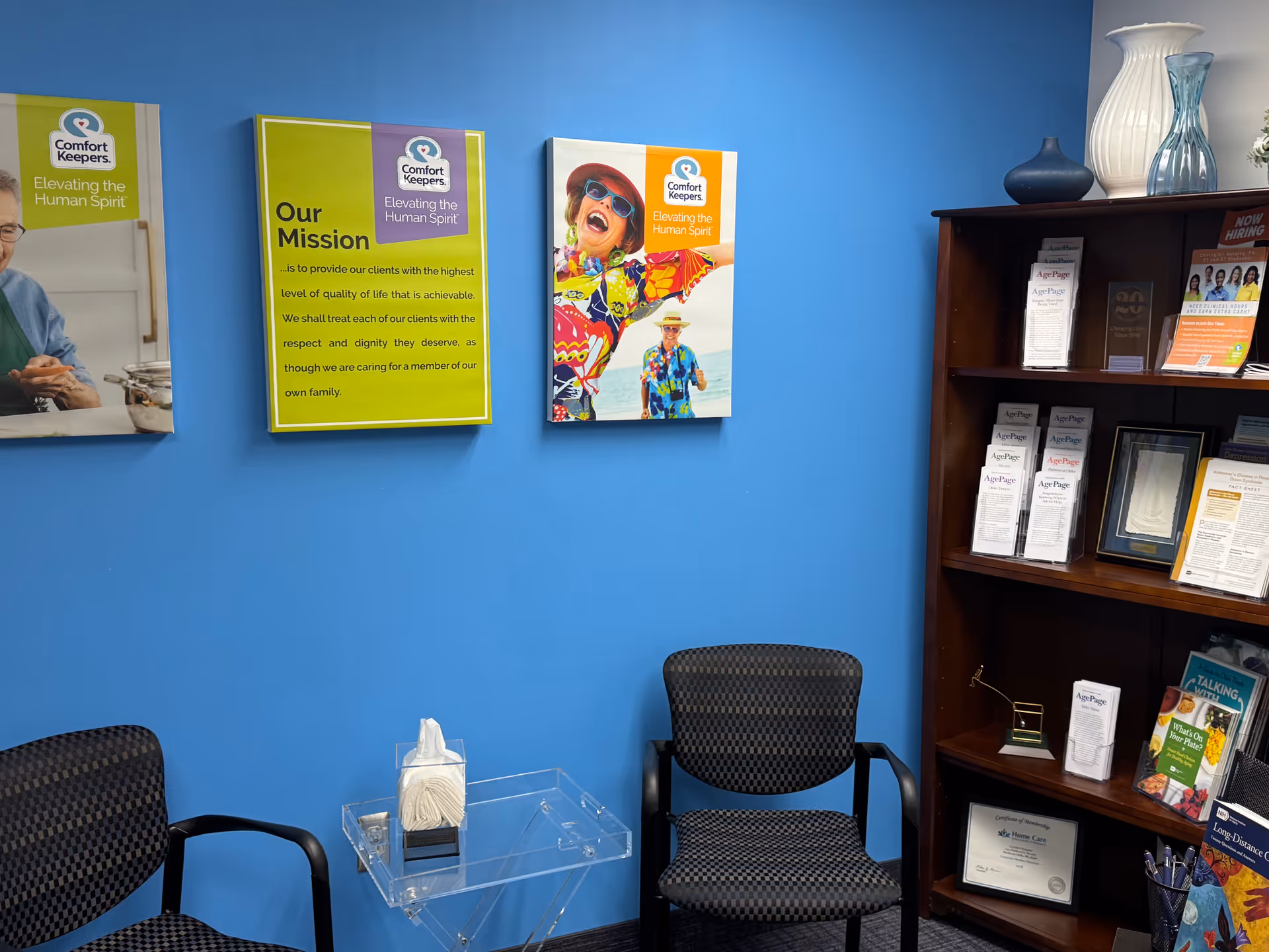 Blue-walled waiting area with chairs, brochure shelf, and Comfort Keepers posters.