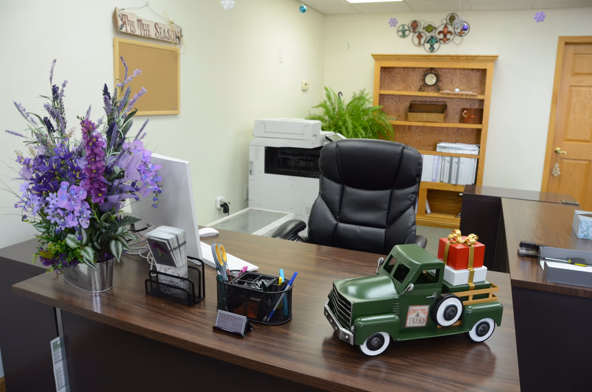 Reception desk with flowers, a toy truck, printer, and shelves in a hospice office.