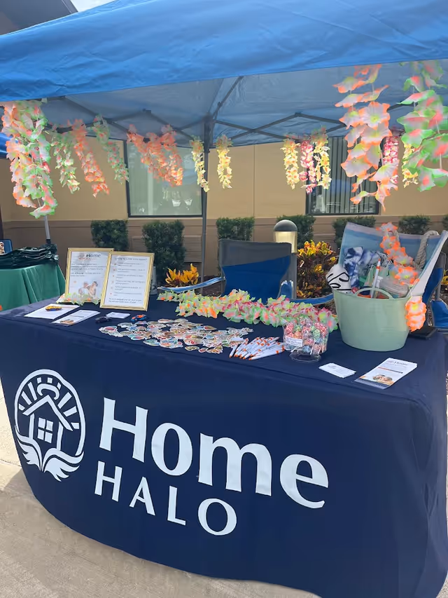 Outdoor promotional booth for Home Halo with leis and informational materials.